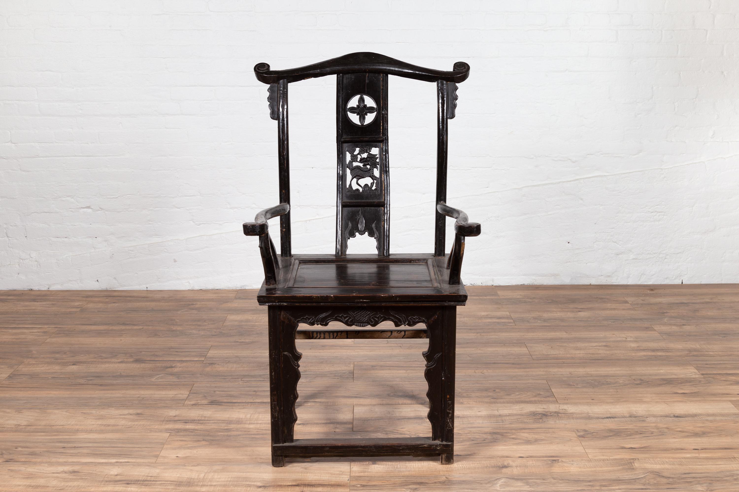A Chinese Ming Dynasty style elmwood scholar's lamp-hanger armchair from the late 19th century, with carved splat, dark patina, curving arms and side stretchers. Born in China in the later years of the 19th century, this scholar's lamp-hanger chair