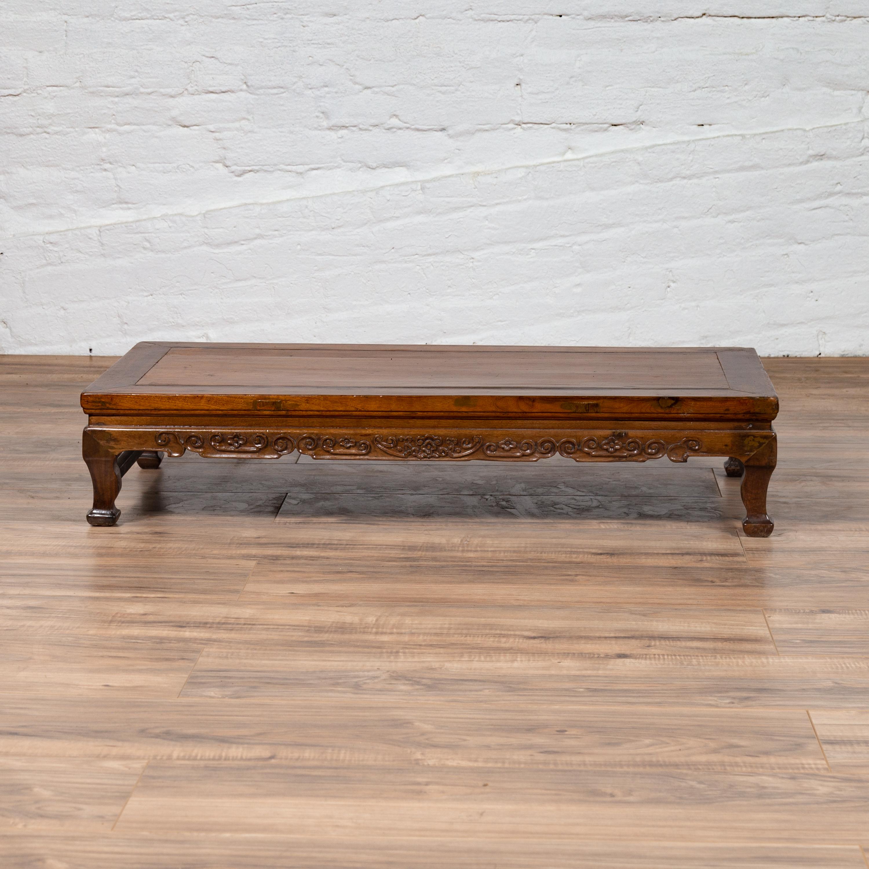 A Chinese antique elmwood low prayer table from the early 20th century, with carved apron and unusual feet. Born in China during the early years of the 20th century, this low prayer table features a rectangular top with central board, sitting above