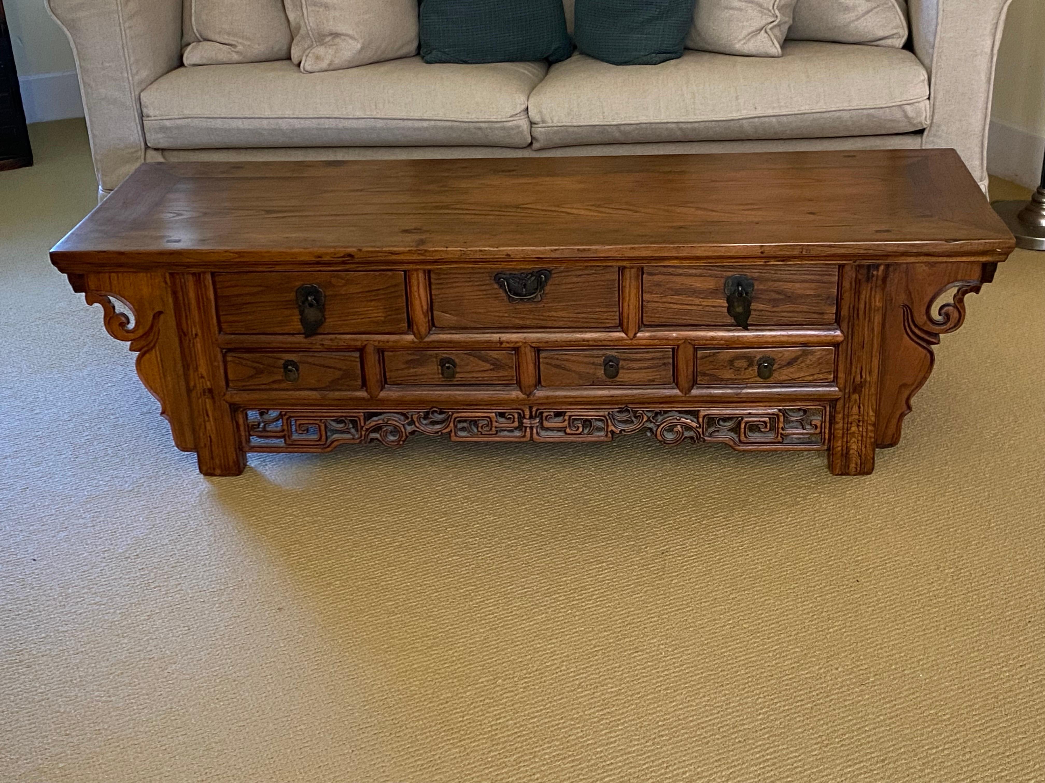 Chinese Elmwood Seven Drawer Altar Coffee Table
Solid Elmwood Low (Kang) Altar Table with three larger drawers atop four smaller drawers over an intricately pierced and carved rail and carved flange.  Back and sides are plain. Light wear to finish,