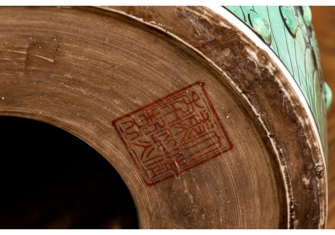 Barrel form with green foliate decoration on a central black ground and with bands of green to the foot and top rims. With pierced double form cash coin handles on two sides as well as a single cash coin pierced motif to the top.

Dimensions: 18