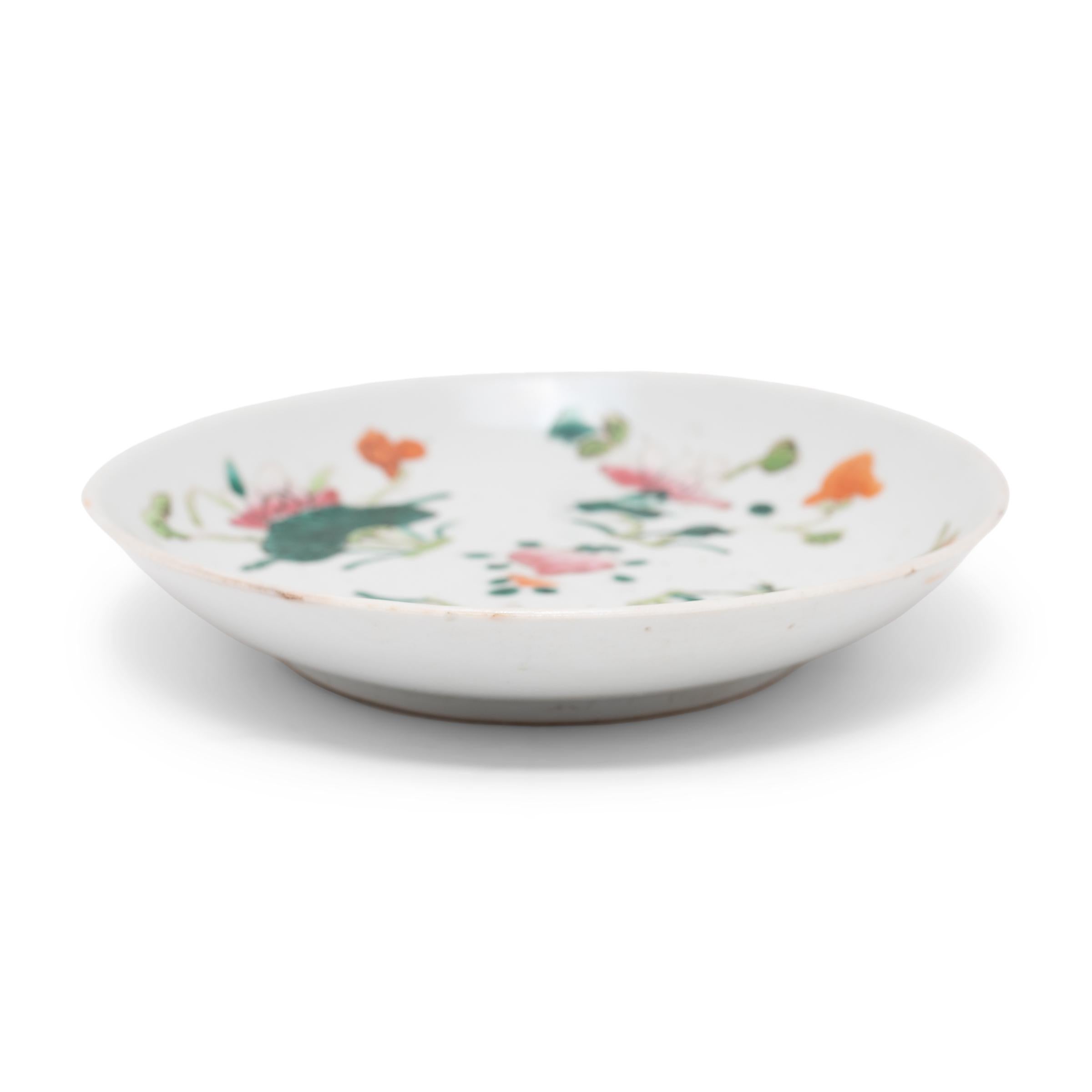 Painted with overglaze enamels in the famille rose style, this small porcelain dish is decorated with a common motif of four flowers symbolizing the seasons. The lotus represents summer, the chrysanthemums represent autumn, the plum blossoms
