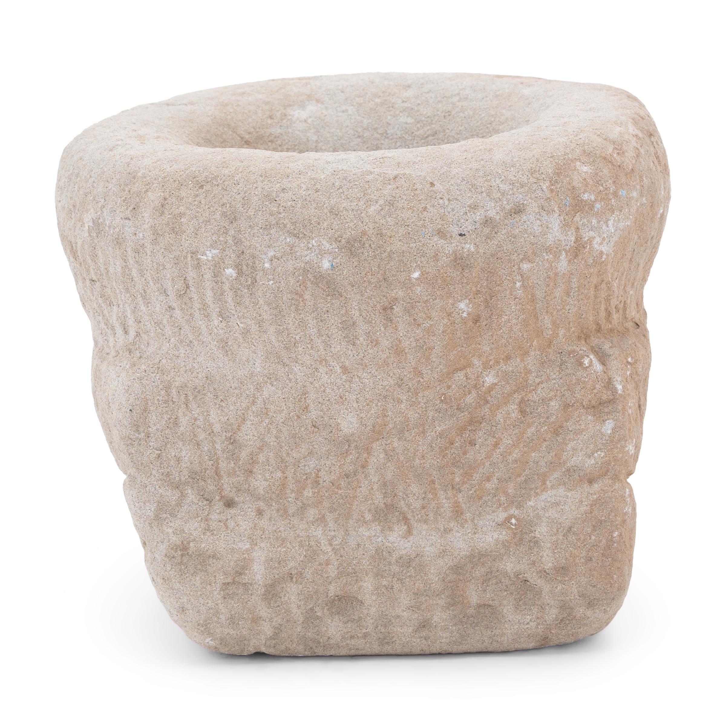 This stone mortar from the early 20th century was once used in a provincial kitchen to grind herbs, spices, rice, and other foods. Hand-carved from a solid block of limestone, the mortar has a tiered shape that transitions from a square base to a