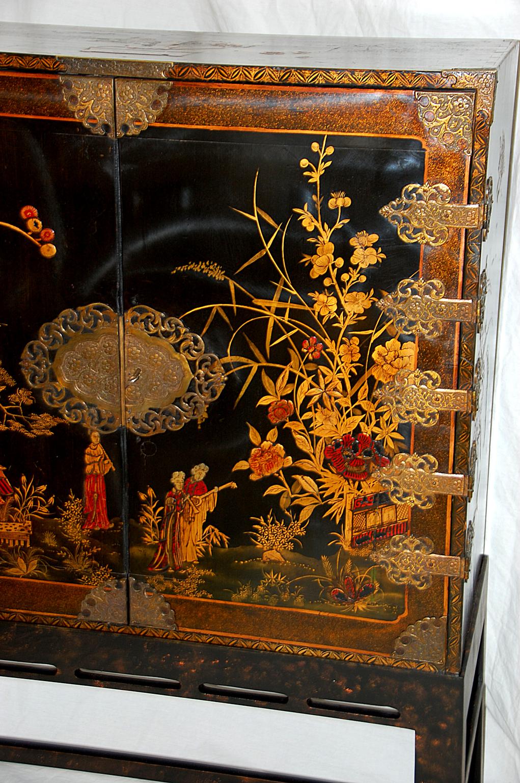 English 19th century black lacquered and hand painted japanned cabinet on custom made stand. This 36 inch wide cabinet has its original naturalistic hand painted decoration in gold and red on black ground and fabulous hand engraved brass hinges and