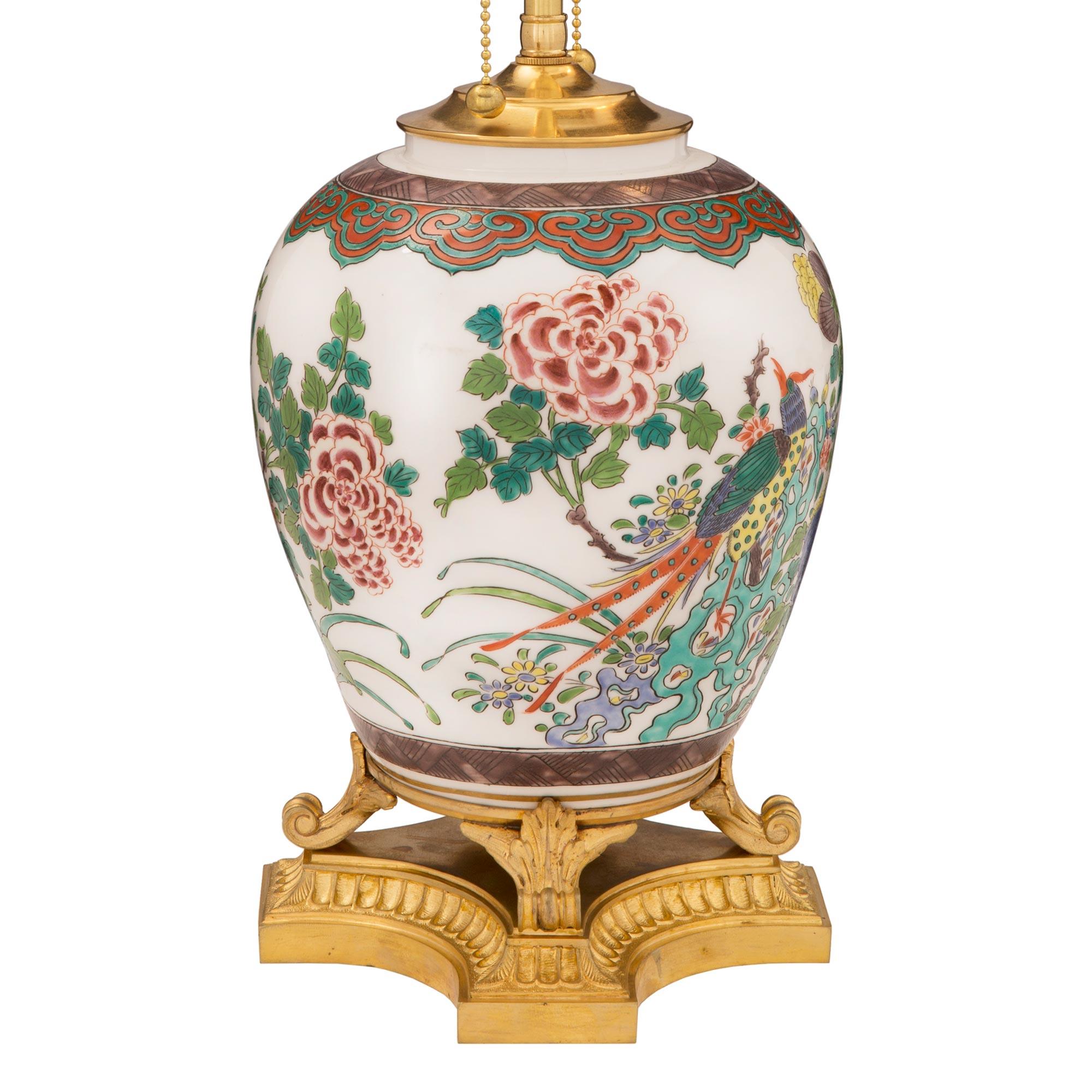 Magnifique lampe en porcelaine Famille Verte d'exportation chinoise du 19ème siècle avec des montures en bronze doré de style Louis XVI du 19ème siècle. La lampe repose sur une très élégante base en bronze doré aux côtés concaves, avec un fin motif