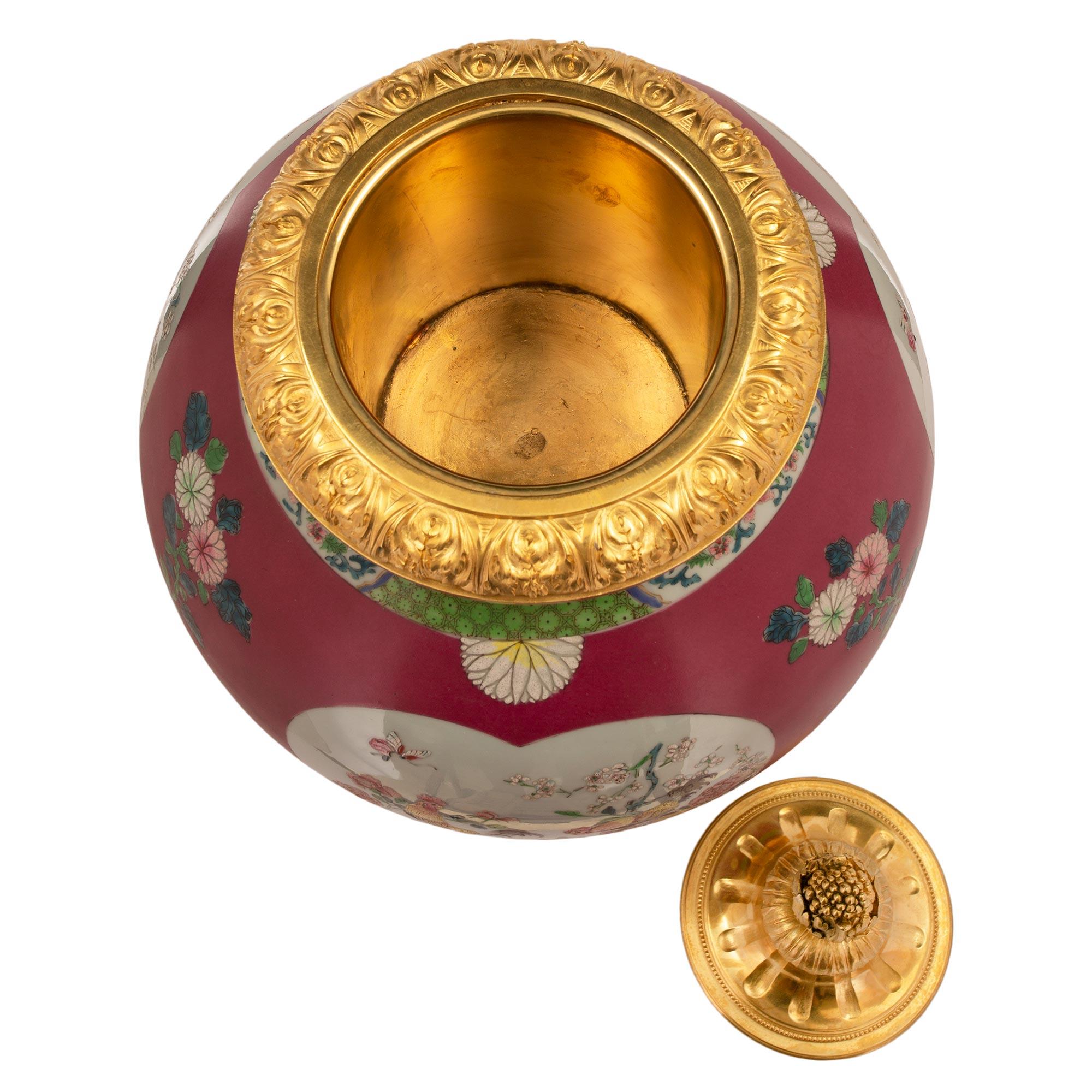 Magnifique urne en porcelaine d'exportation chinoise du 19e siècle avec de remarquables montures en bronze doré de style Louis XVI du 19e siècle. L'urne est surmontée d'une élégante base carrée en bronze doré avec des coins concaves et de fins