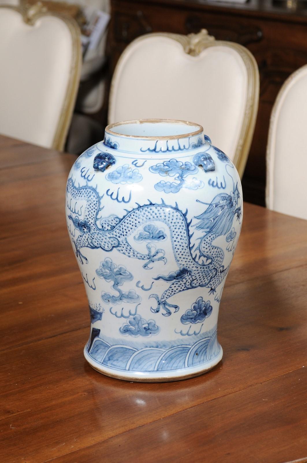A Chinese Export blue and white porcelain vase from the 20th century, with dragon motifs. Created in China during the 20th century, this blue and white porcelain vase features a nicely curving body adorned with dragon motifs surrounded by clouds,