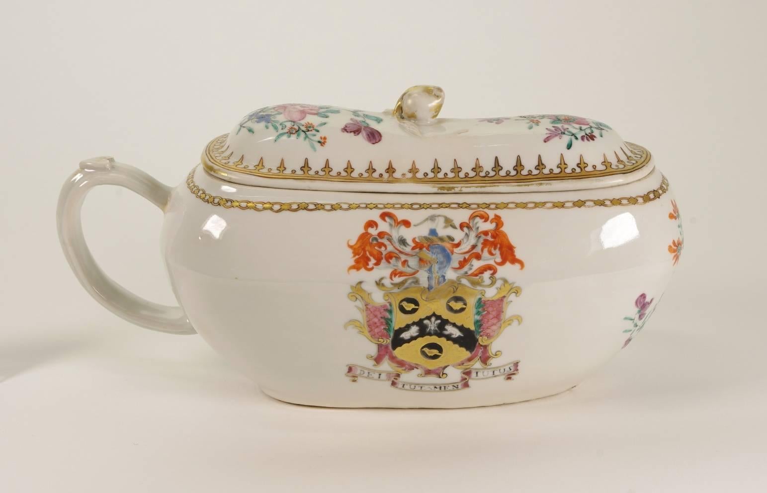 Chinese Export porcelain armorial bourdaloue, the cover with a spearhead border and gilt finial, the body with a chain border; each piece painted with flower sprays; the handle with a heart shaped thumb-piece, decorated with the arm of