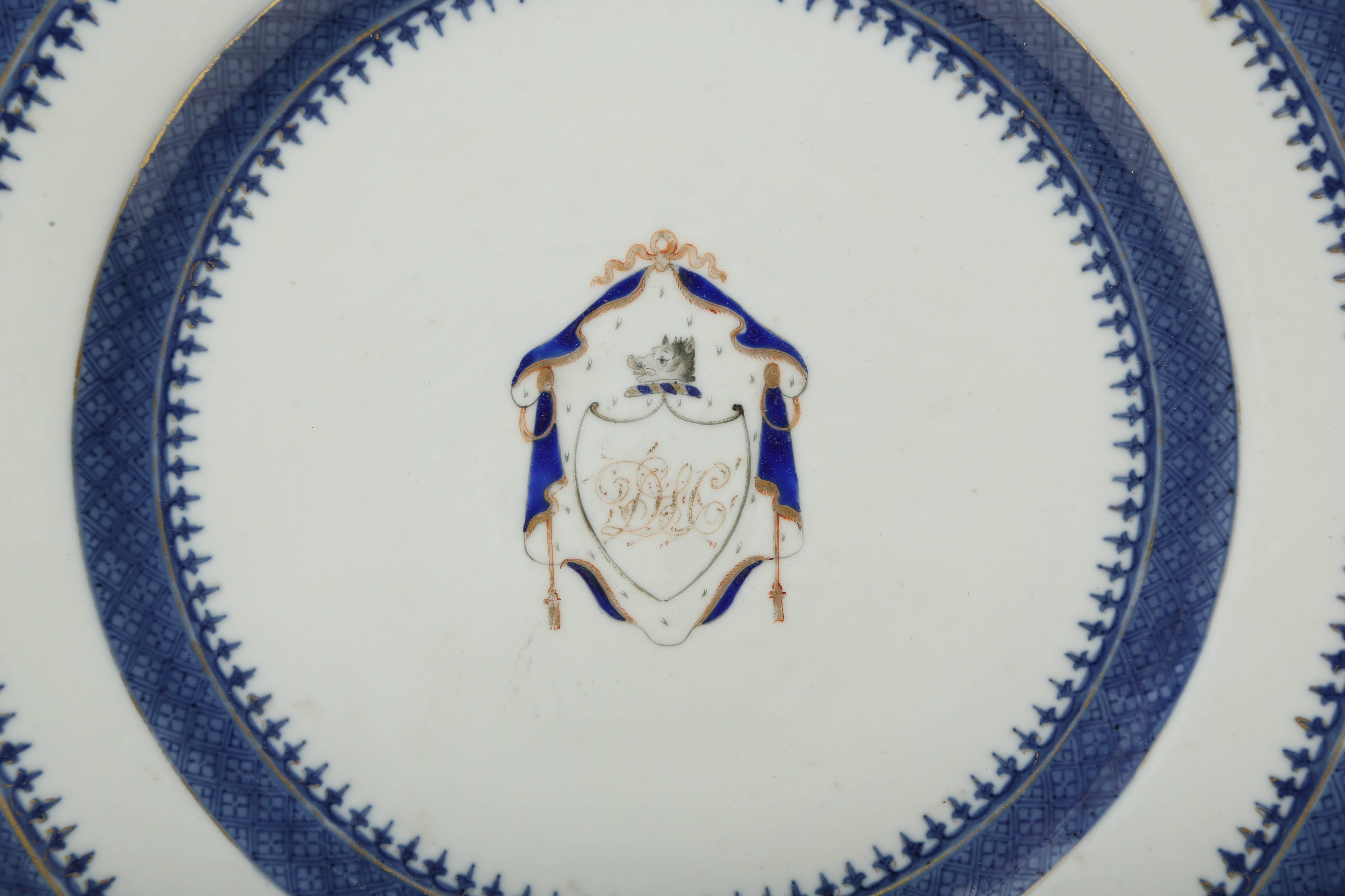 Chinese export porcelain armorial plate hand decorated in underglaze blue and overpainted with cobalt blue and gold enamel.  In the central well there is the crest of a shield with the initials D.L.C.  under a boar's head surrounded by swagged