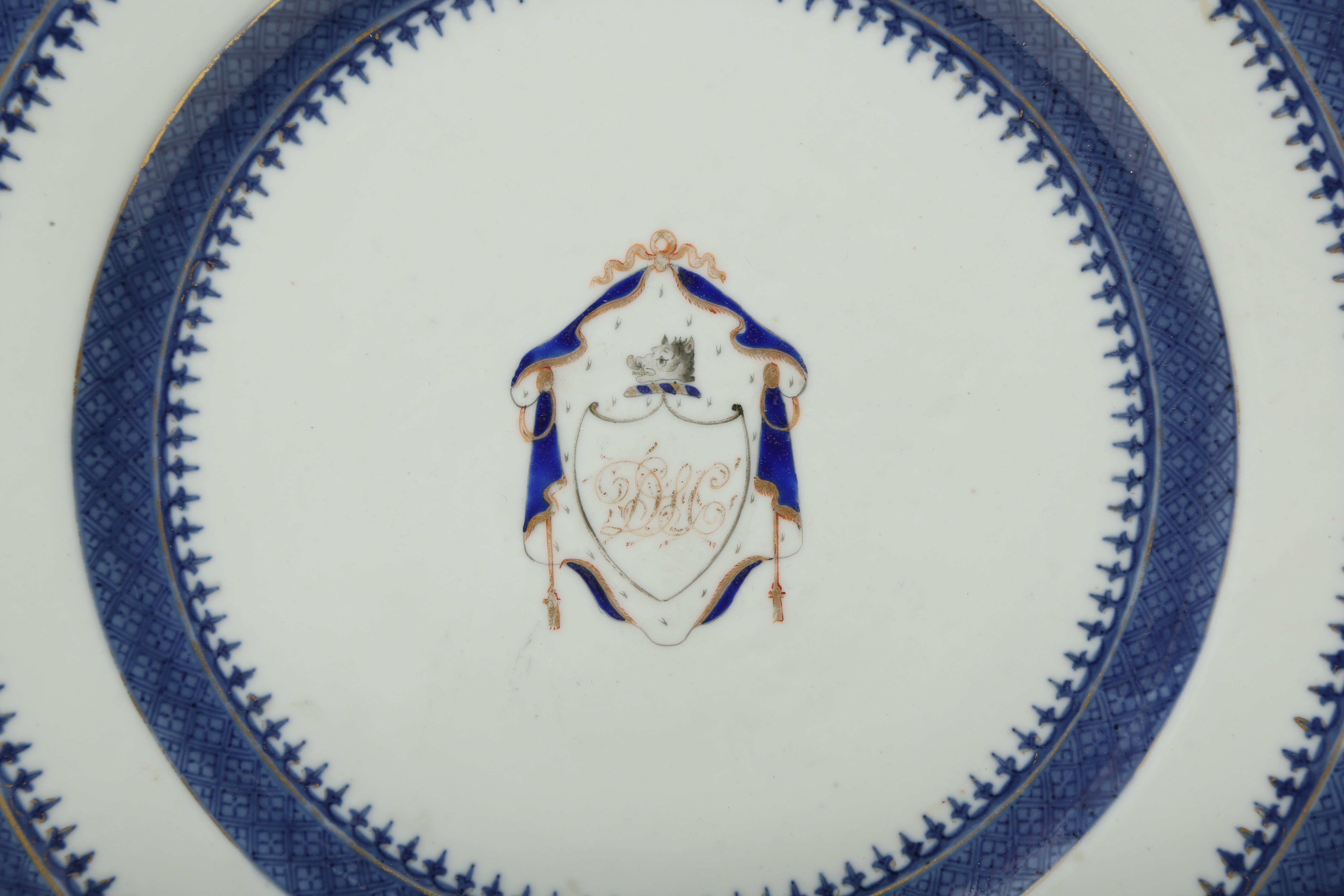 Chinese export porcelain armorial plate hand decorated in underglaze blue and overpainted with cobalt blue and gold enamel. In the center there is the crest with the initials D.L.C. under a boar's head surrounded by swagged drapes and topped with