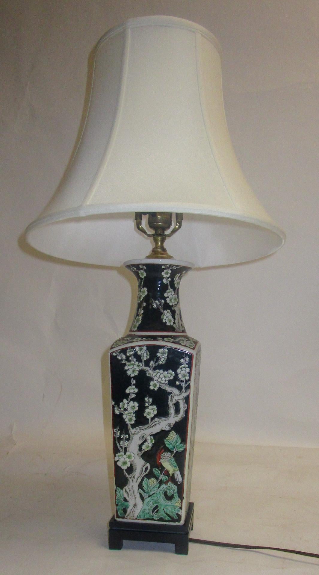 Chinese Export table lamp made from a graceful vase decorated with colorful birds, dogwood branches and fruit on an orange peel surface. The hardware is brass and the vase is perched on a stylish wooden base. The unusual greens and crimson colors