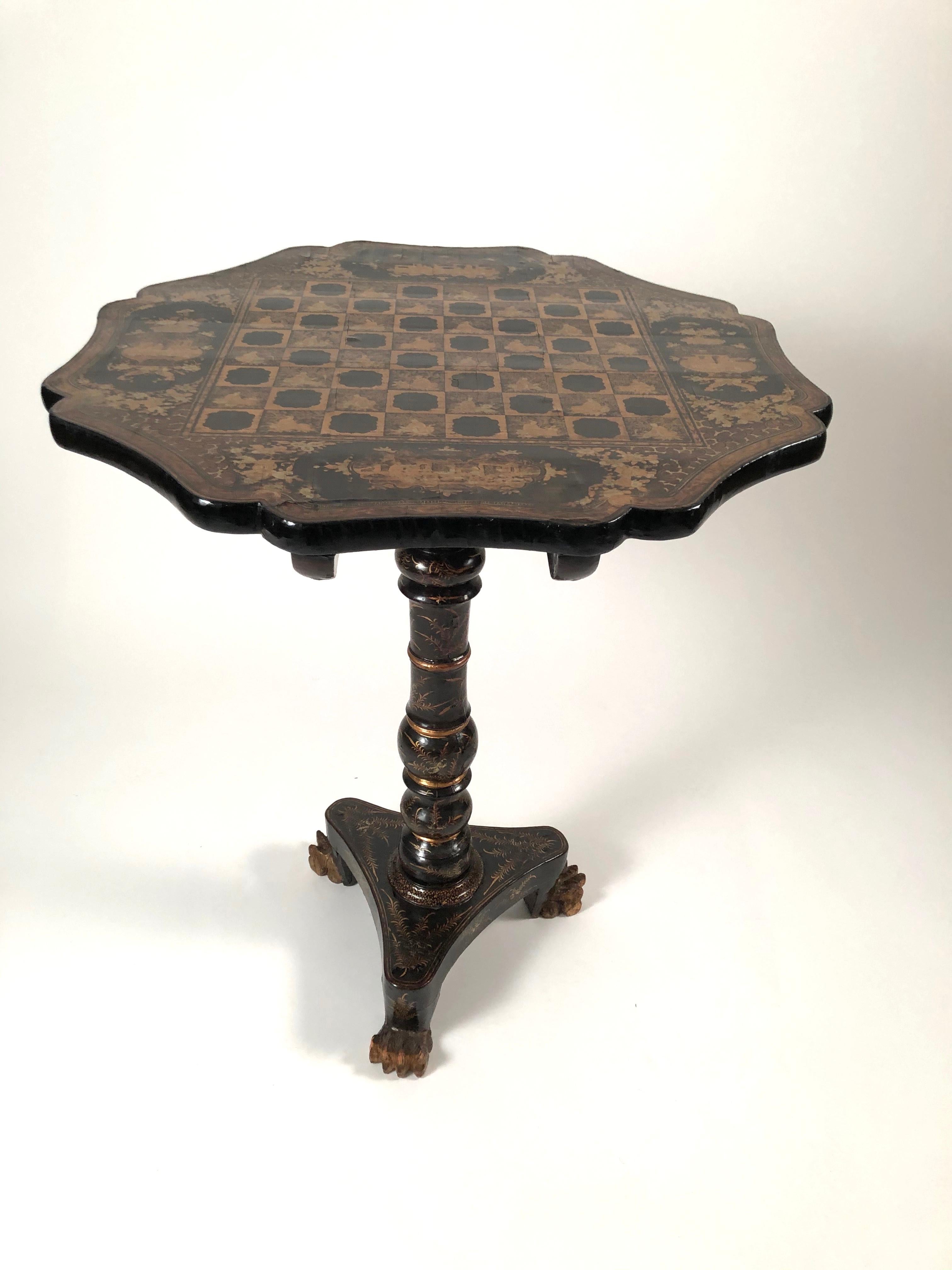 A fine quality black lacquered and gilded tilt-top games table, Chinese Export for the English and American markets, circa 1810, the serpentine octagonal shaped top, beautifully decorated with a finely drawn penwork chess and checker board,