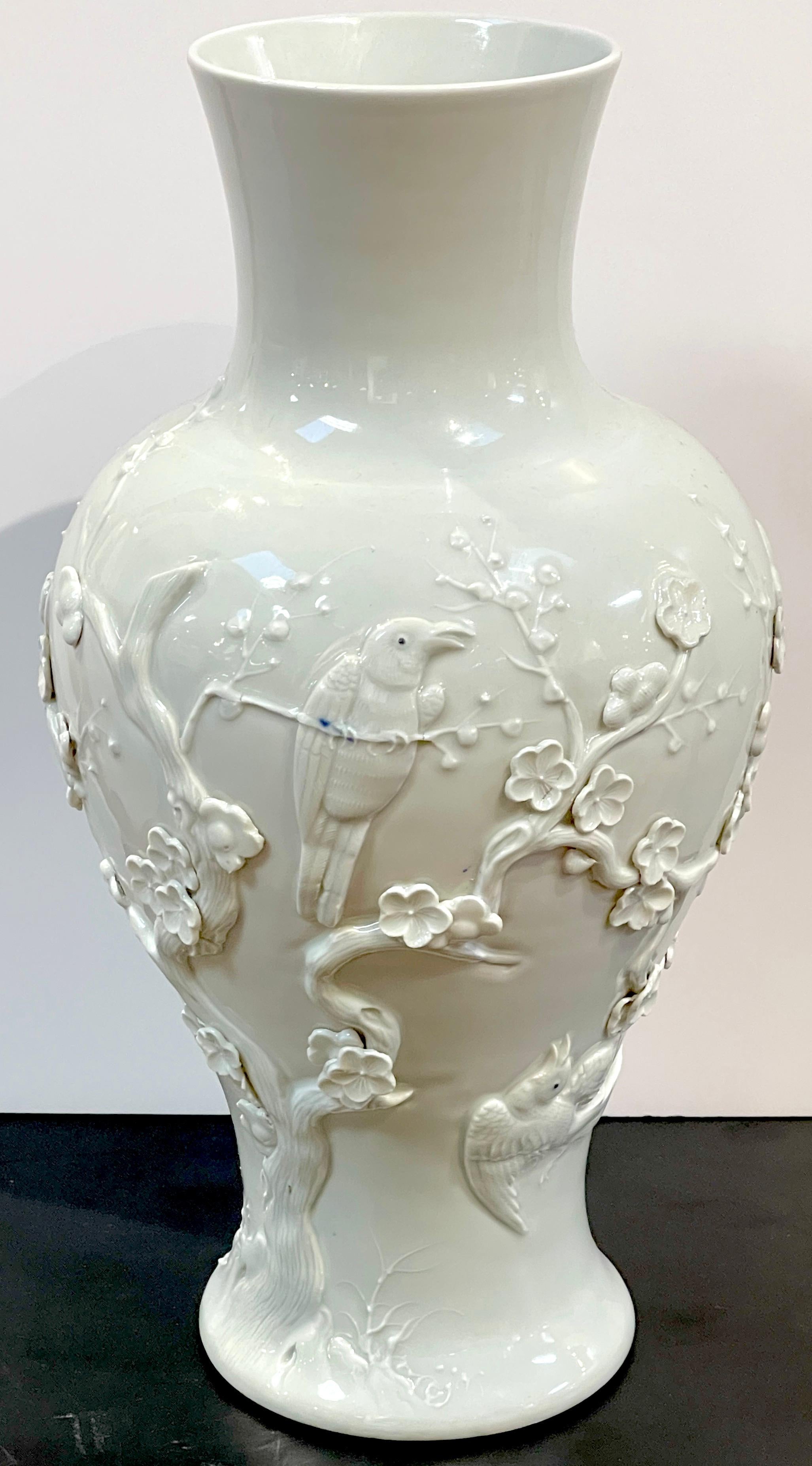 Chinese Export Blanc de Chine Prunus & Bird Motif Relief Vase, Slender 
China, 20th Century,  Incised honorific Jiaqing four-character mark 

Enhance your interior with this exquisite Chinese Export Blanc de Chine Prunus & Bird Motif Relief Vase, a