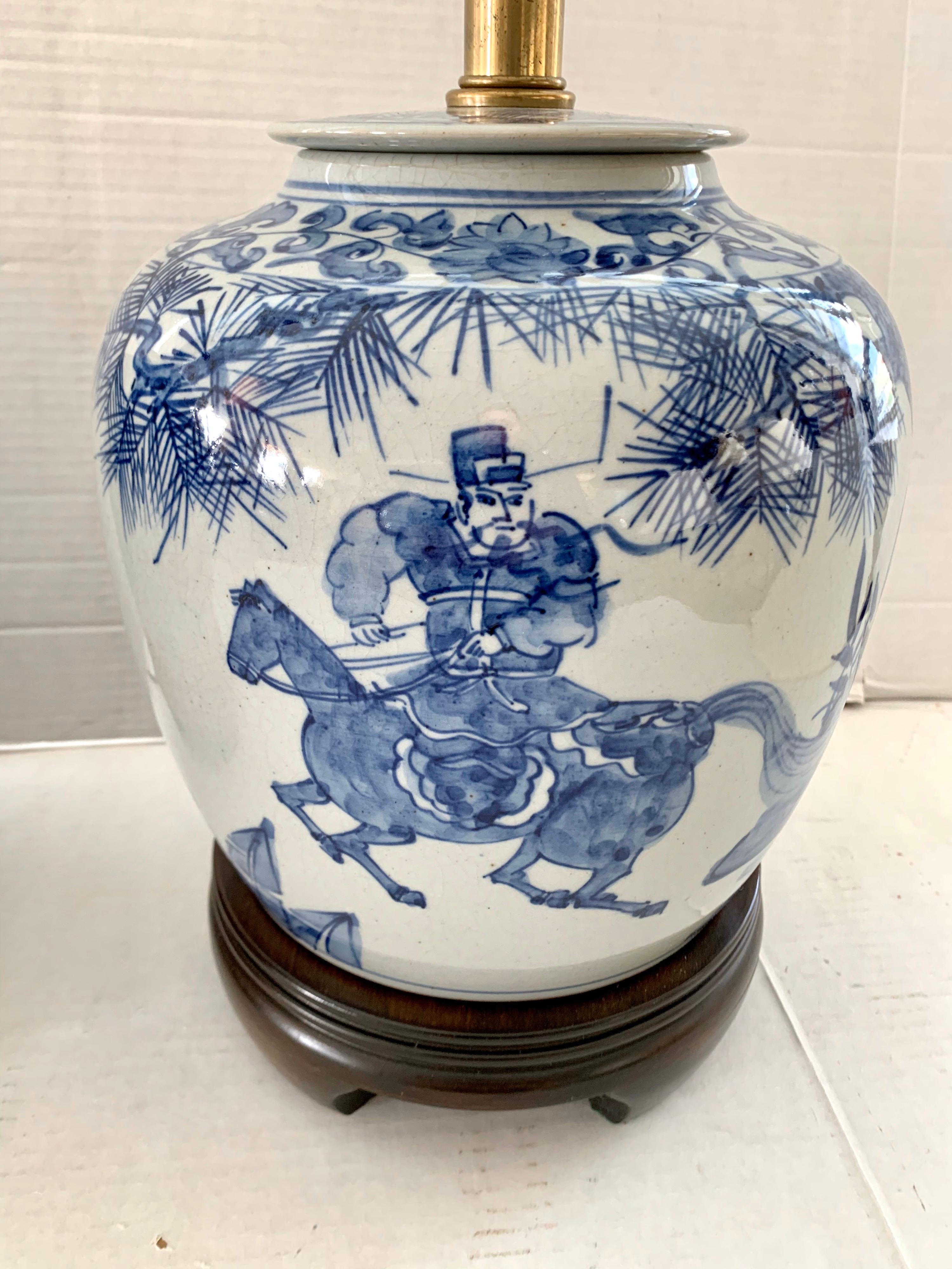 Pair of Chinese ginger jar lamps were handcrafted and hand painted 30 years ago, following traditional Qing Dynasty craftsmanship methods and design.
Hand painted ceramic base with blue and white glaze on a carved wood base. They feature a man on