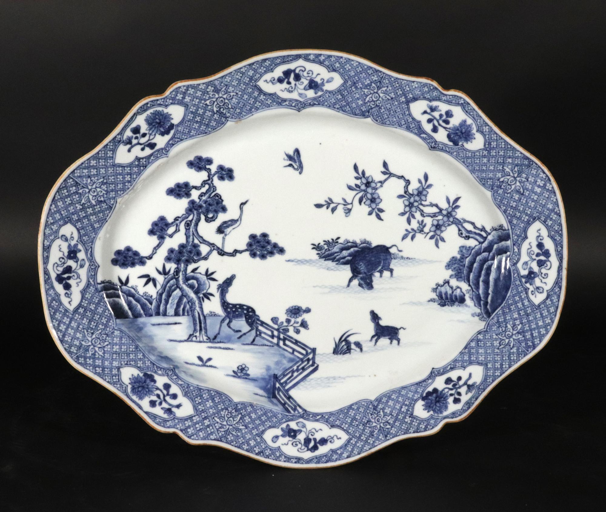 Plat en porcelaine bleue et blanche d'exportation chinoise avec buffle et cerf,
Circa 1770

Ce plat ovale en porcelaine d'exportation chinoise de style rococo est doté d'une large bordure en forme de couche avec des panneaux de fleurs en forme.  Le