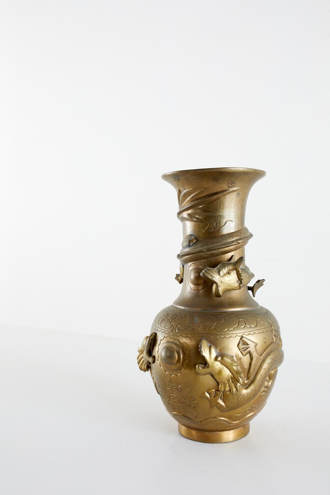 Patinated brass Chinese export vase featuring a high relief design of three dragons. Two dragons are depicted on the body chasing an orb or pearl sun design, and one dragon is on the neck. Maker's mark on bottom.