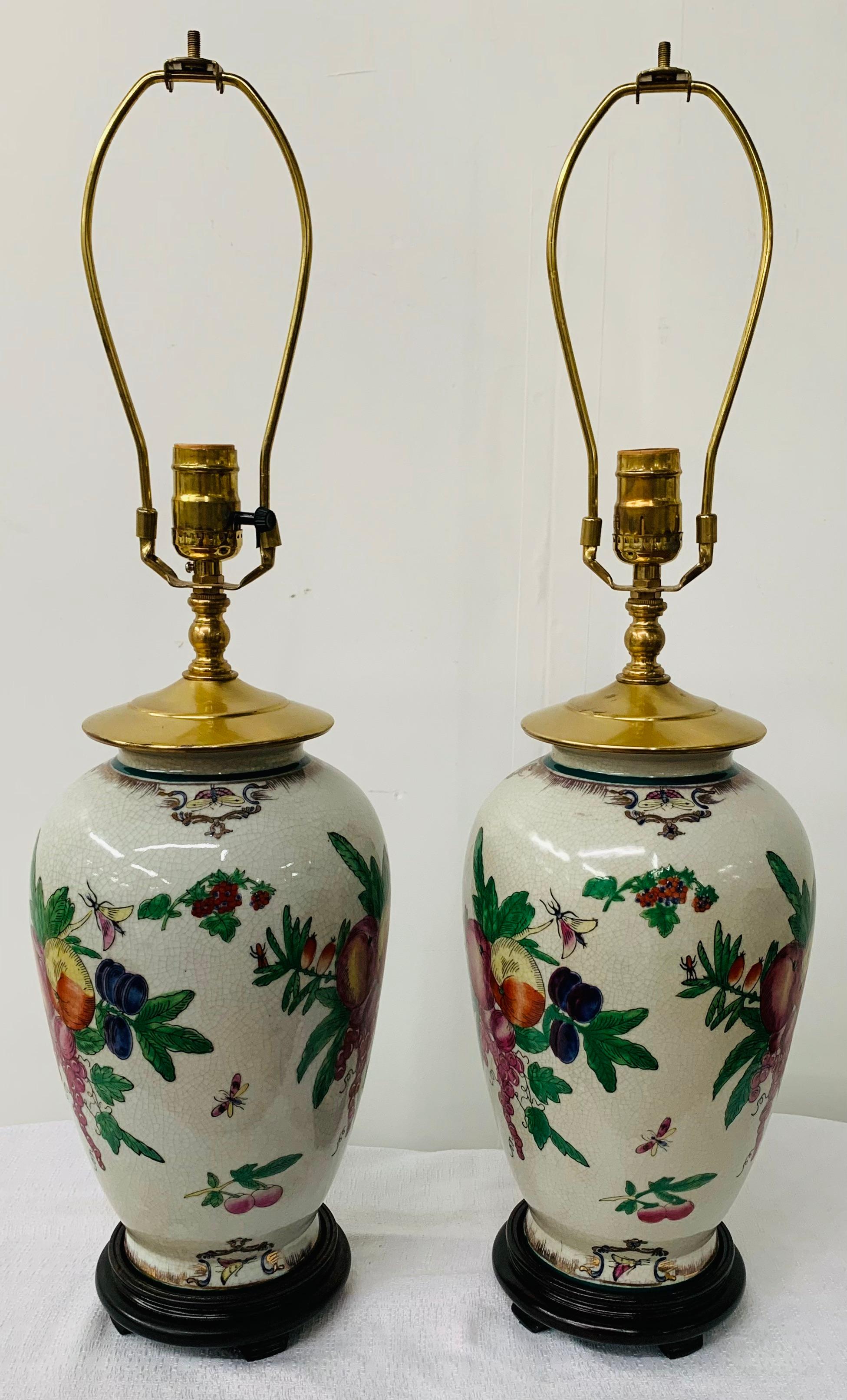 A beautiful pair of Chinese Export table lamps featuring an exquisite flora design. Both lamps sit on wooden carved base and come with white shades. 

This pair of lamps will add style to your bedroom, living room, study/office space or entry