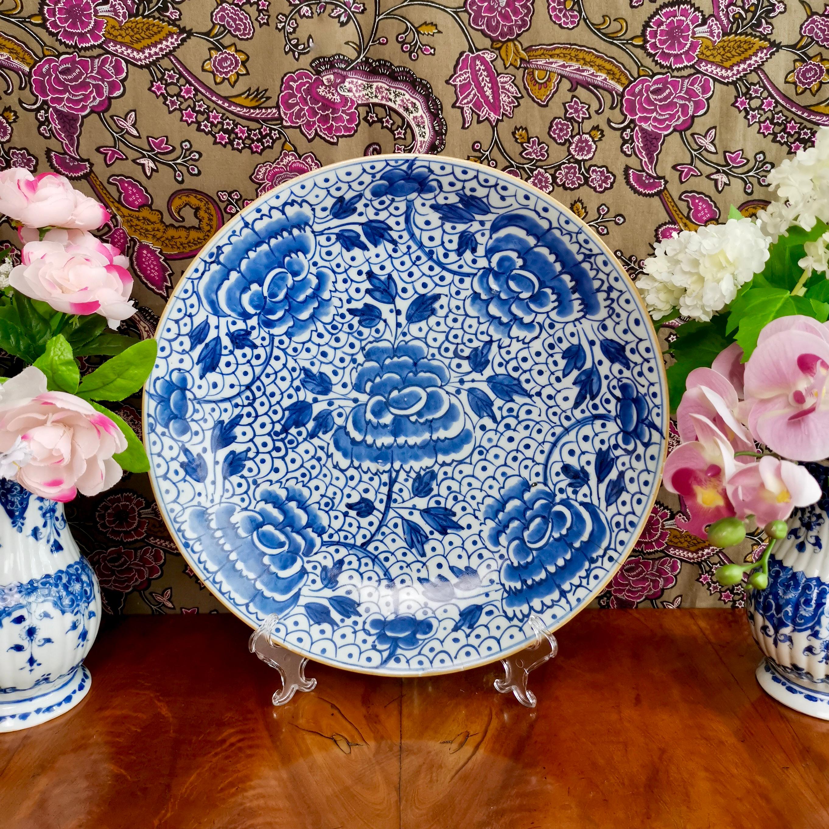 This is a beautiful large porcelain charger made in China for export to the West. The charger dates from the late KangXi era in the early 18th Century.

The charger is lightly potted with a bluish matte glaze and has a beautiful underglaze blue