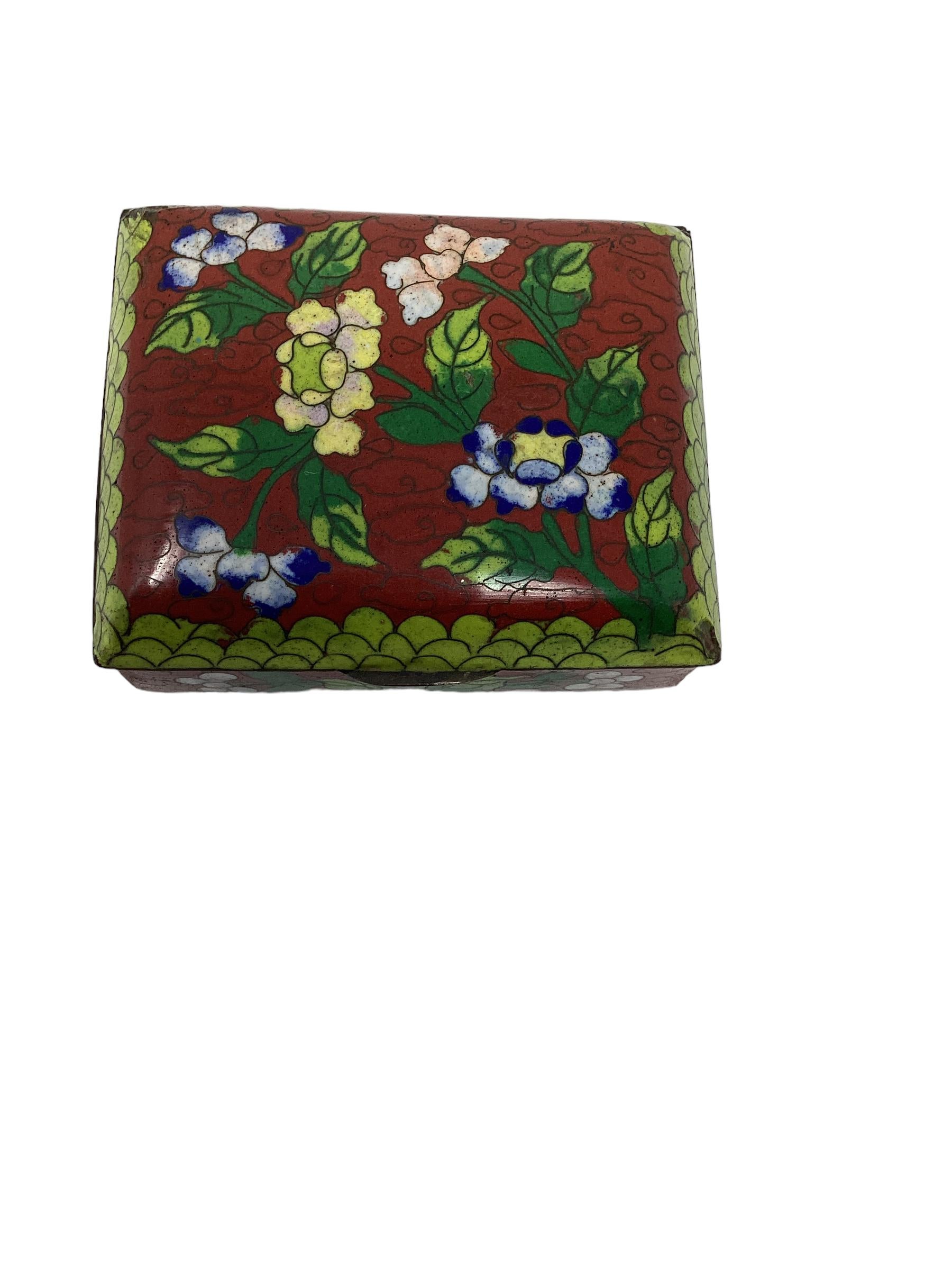 Lovely Chinese export cloisonné box made of brass and enameled with a beautiful floral pattern in beautiful colors of red, green, blue and red. The box rests on ball feet. This chinoiserie box is marked china and dates from 1900-1920. This