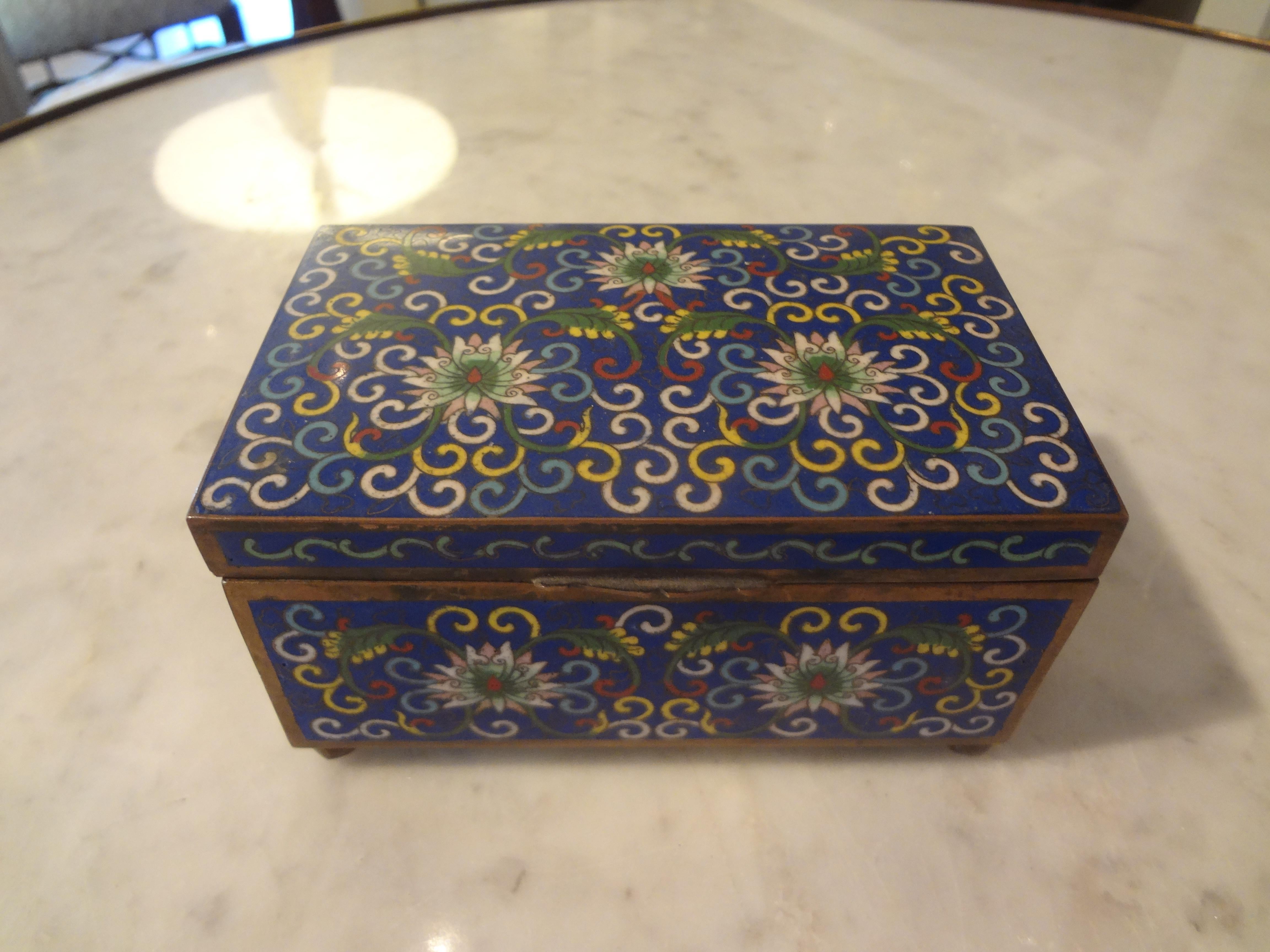 Lovely Chinese export cloisonné box made of brass and enameled with a beautiful floral pattern resting on ball feet. This chinoiserie box is marked China and dates from 1900-1920. This good sized decorative box was most likely a cigarette box or