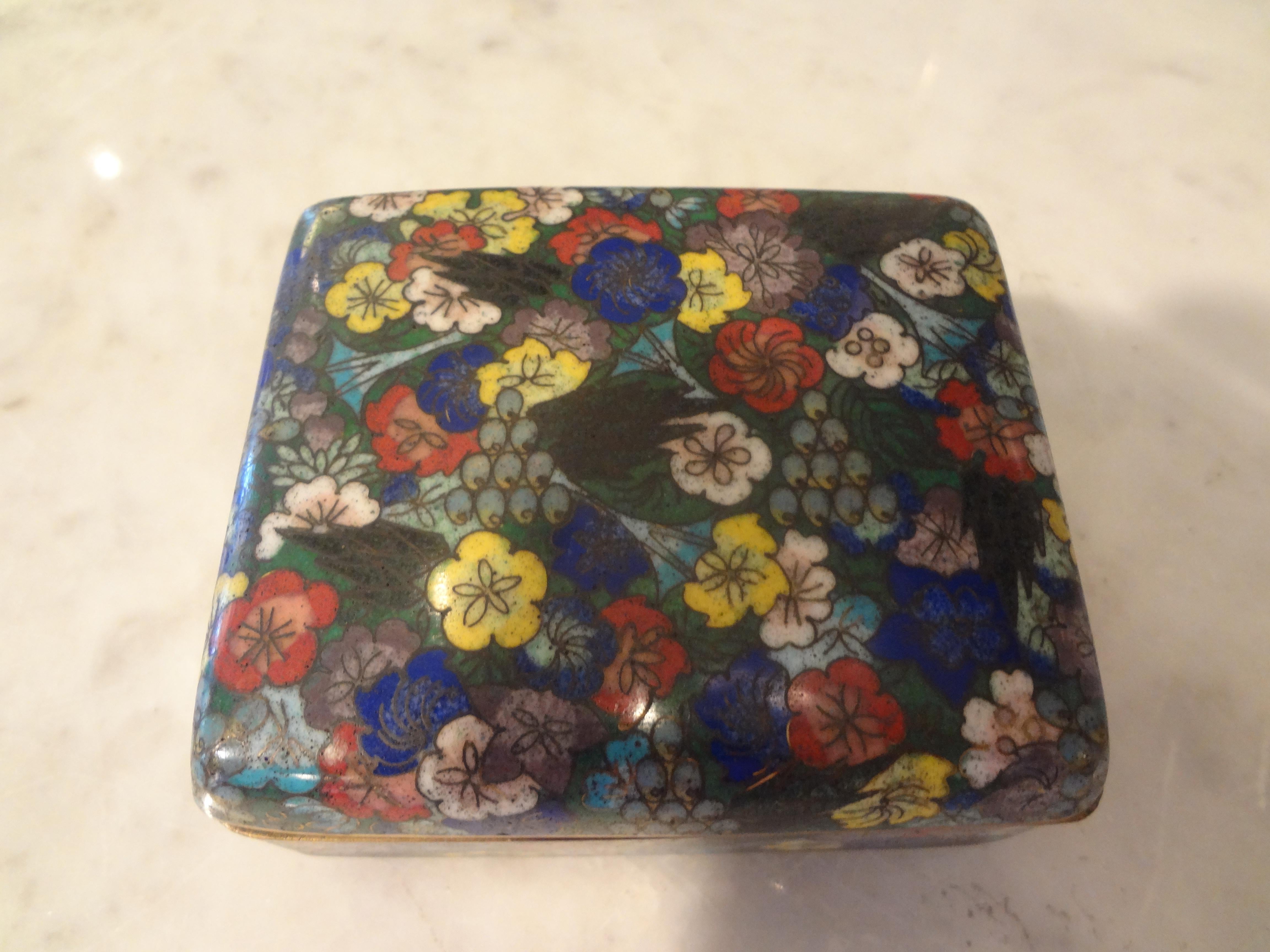 Lovely Chinese export cloisonné box made of brass and enameled with a beautiful floral pattern resting on ball feet. This chinoiserie box is marked china and dates from 1900-1920. This decorative box was most likely a cigarette box or trinket box