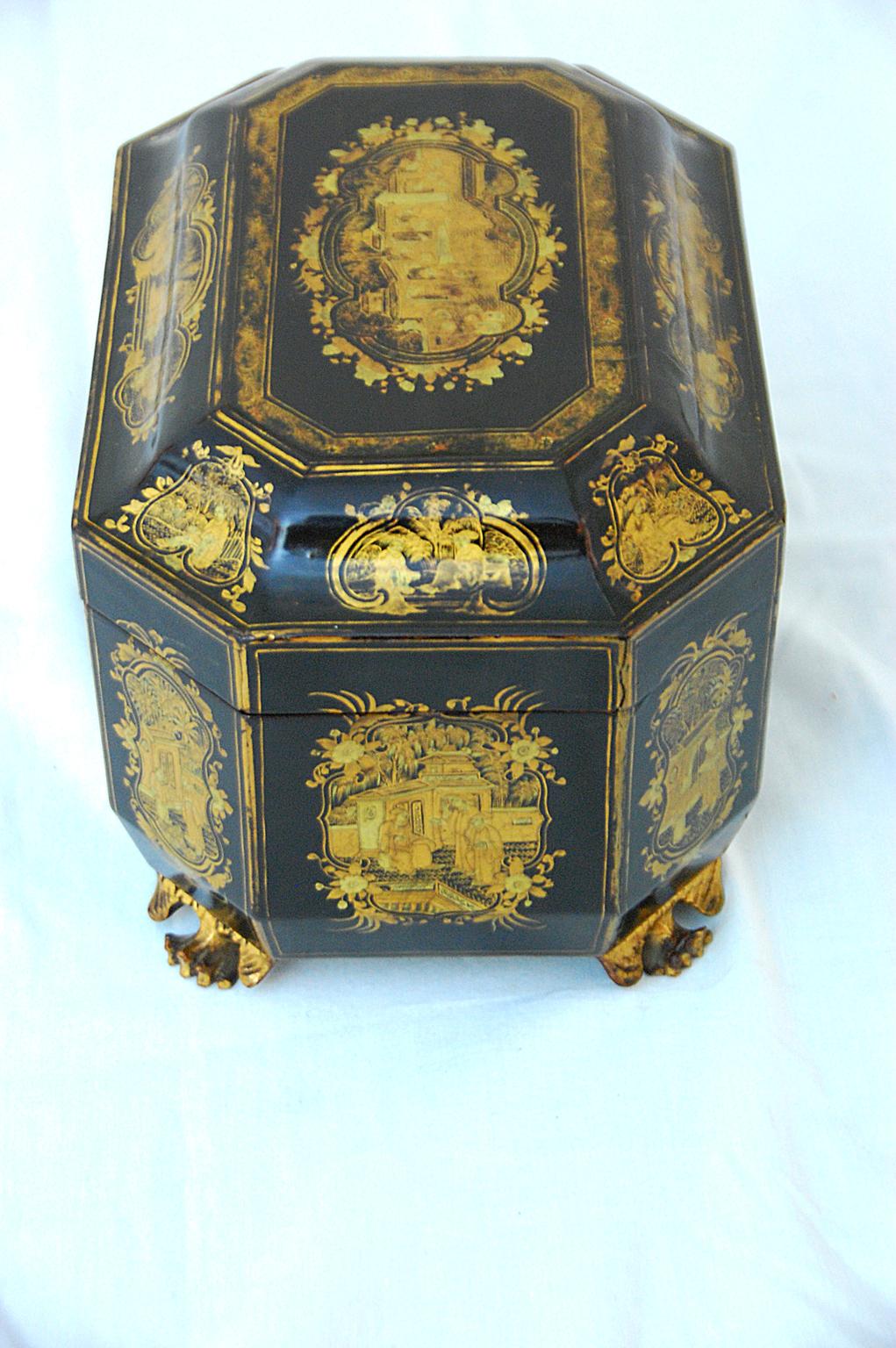 Chinese export lacquered hand painted octagonal chinoiserie teacaddy , black with gold decoration. The interior has two hand engraved pewter tea boxes, each with double lids to keep the tea fresh. This fine teacaddy has hand carved feet, ogee shaped
