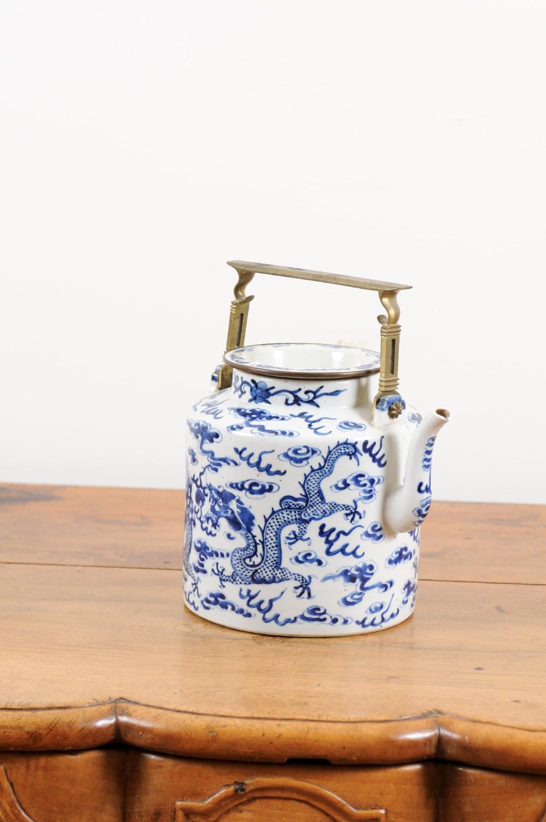 A Chinese Export blue and white porcelain teapot from the early 20th century, with dragon and cloud motifs. Created in China during the early years of the 20th century, this porcelain teapot features a circular body adorned with auspicious dragon
