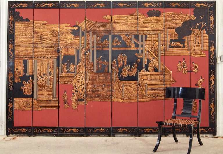 Fantastic Chinese export eight panel coromandel screen featuring a dramatic Imperial palace in gilt with a coral red background. Black lacquered panels incised with gilt depicting figures engaged in leisurely activities around an Imperial court