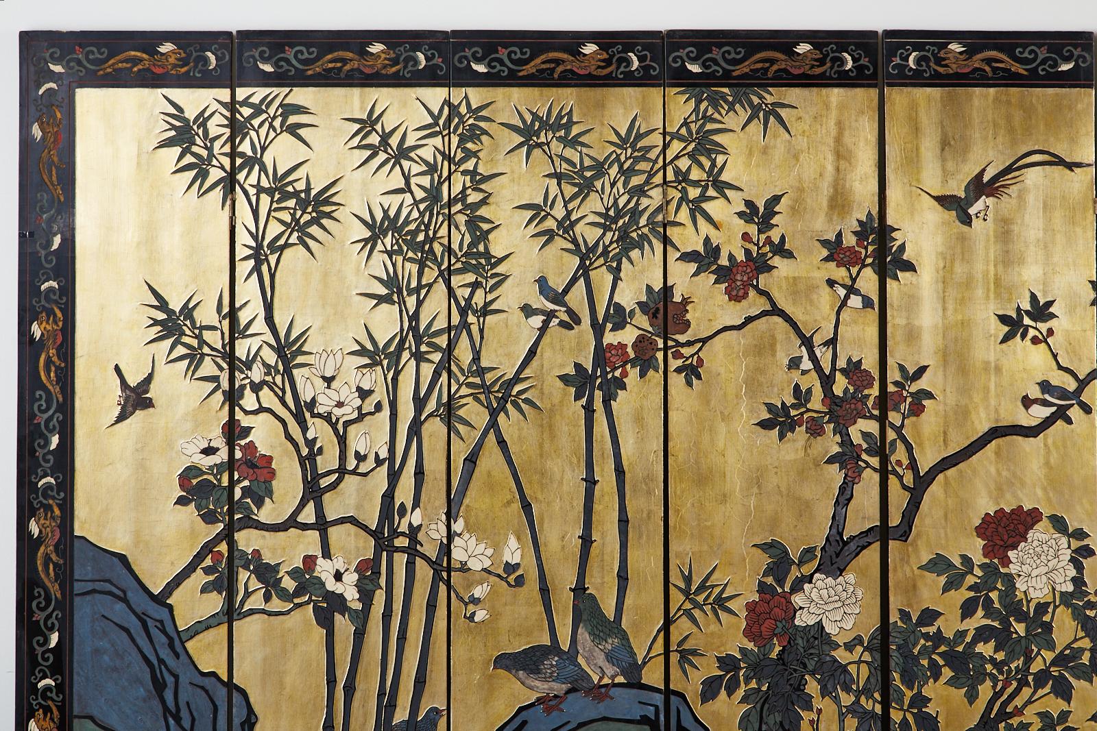 Fantastic Hollywood Regency period Chinese export eight-panel lacquered coromandel screen. Features a flora and fauna landscape with a stunning gilt background. The incised lacquer panels are colored with vibrant reds, whites, blues, and greens. The