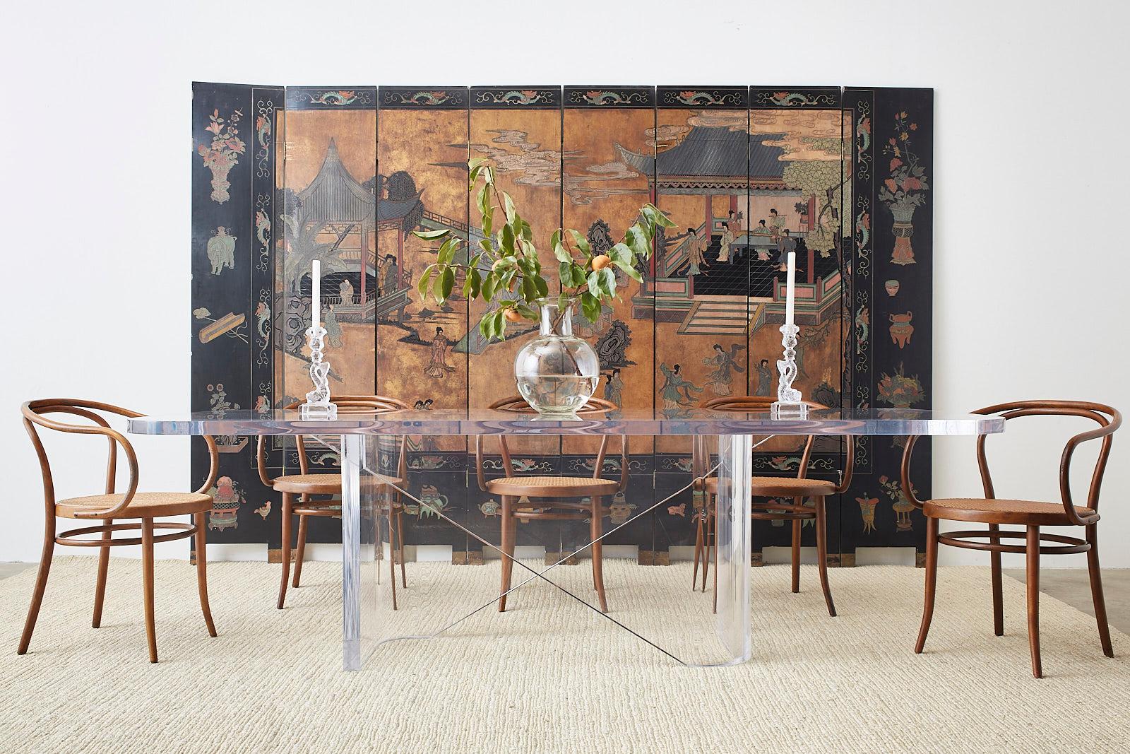 Gorgeous Chinese export eight panel coromandel screen featuring a courtyard scene with beauties amid pagodas. The screen has a gilt background in the center that has faded into a rich hue accented by muted colors of added reds and teal. Bordered