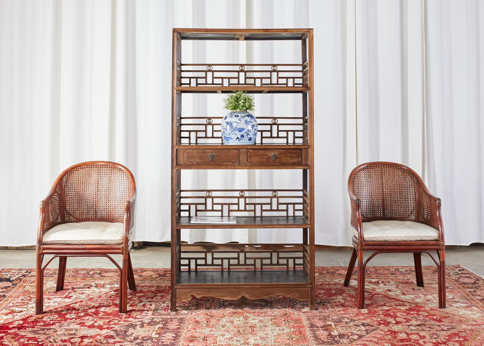 Qing dynasty style Chinese export bookcase or scholar's display shelf étagère constructed from elm. The four shelf bookcase features an open fretwork lattice design on the back and sides of each shelf. The middle shelf has two storage drawers with