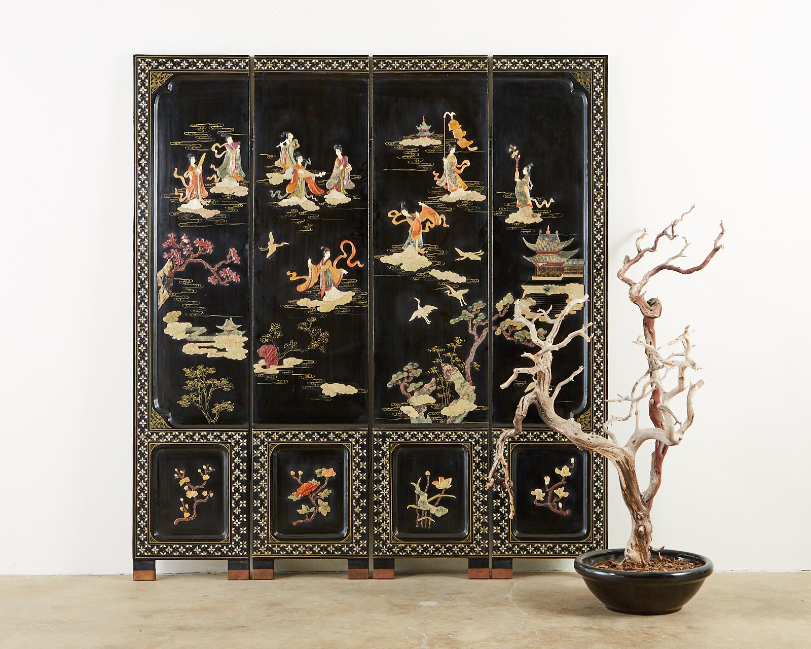 Stunning 20th century Chinese export four-panel lacquered Coromandel screen featuring hand carved soapstone beauties in a floral, pagoda landscape. The highly decorative screen has recessed borders which showcase intricate mother of pearl inlay and