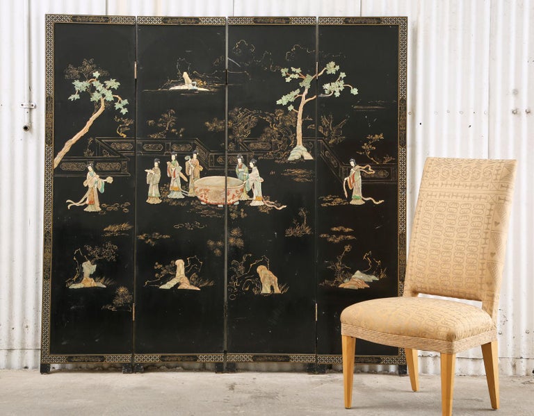 Distinctive Chinese export four-panel coromandel screen featuring carved hardstone and soapstone decoration. The screen depicts a group of beauties in colorful flowing robes. The parcel-gilt landscape is decorated with two large carved stone trees.