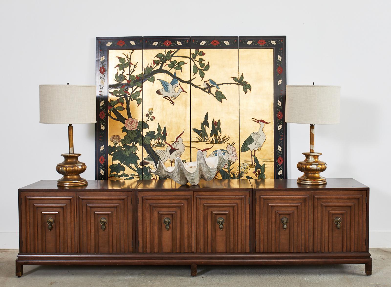 Dazzling Chinese export lacquered four-panel coromandel screen featuring a flora and fauna waterscape with stylized cranes. The carved lacquer panels are embellished with vivid colors of natural pigments on an amazing gold leaf square ground. The