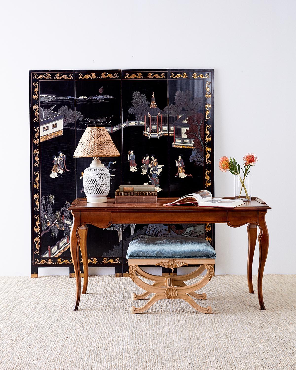 Elegant Chinese export four panel lacquered coromandel screen. Featuring a courtyard scene with musicians and dancers amid pagodas. The figures are dressed in brightly colored robes that are showcased against the black ground. The front panels are