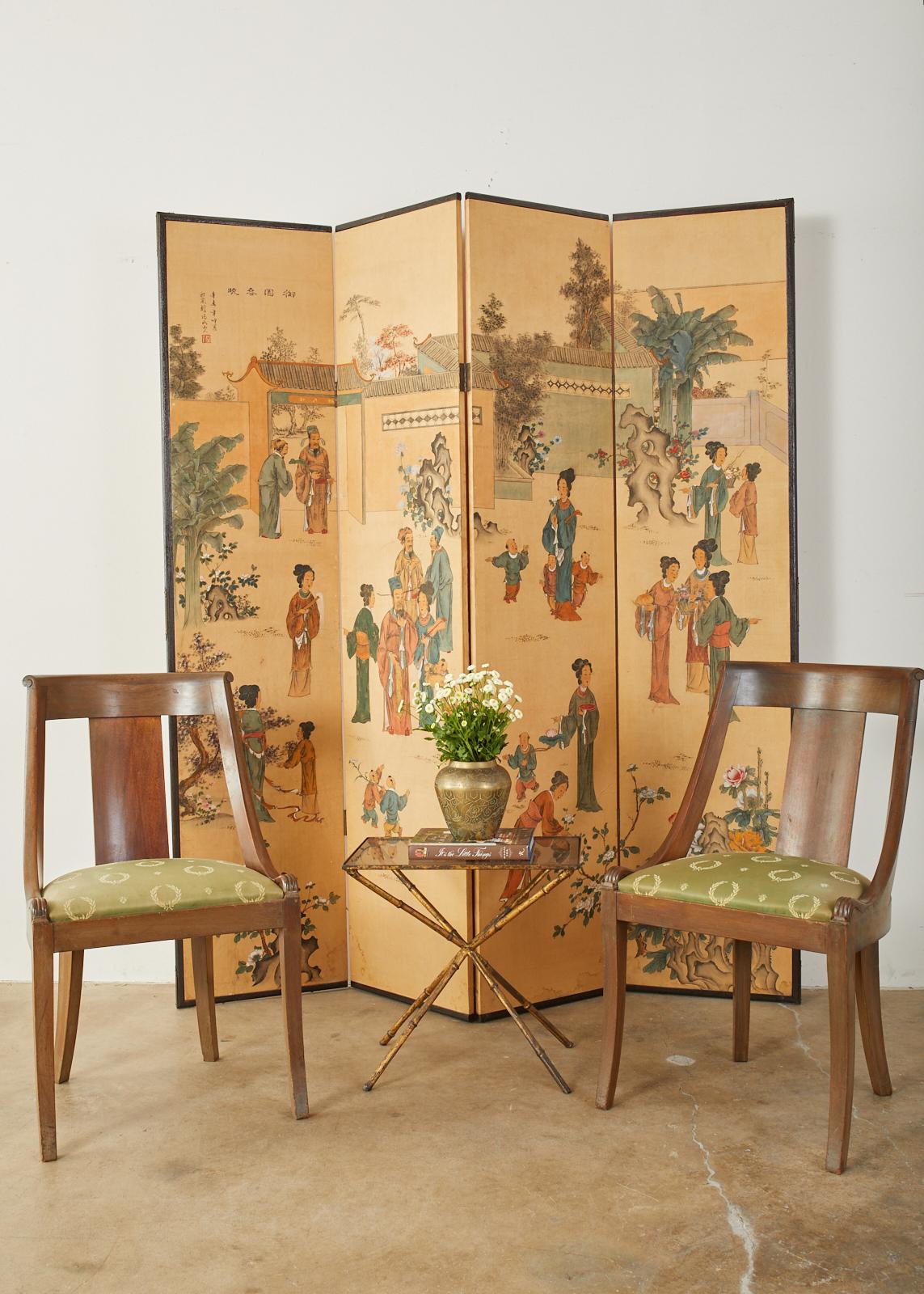Colorful Chinese export four-panel folding wallpaper screen depicting figures in leisurely activities. Vibrant colors from florals and elaborate robes decorate the scene over a saffron yellow background. Titled and signed with a seal in the upper