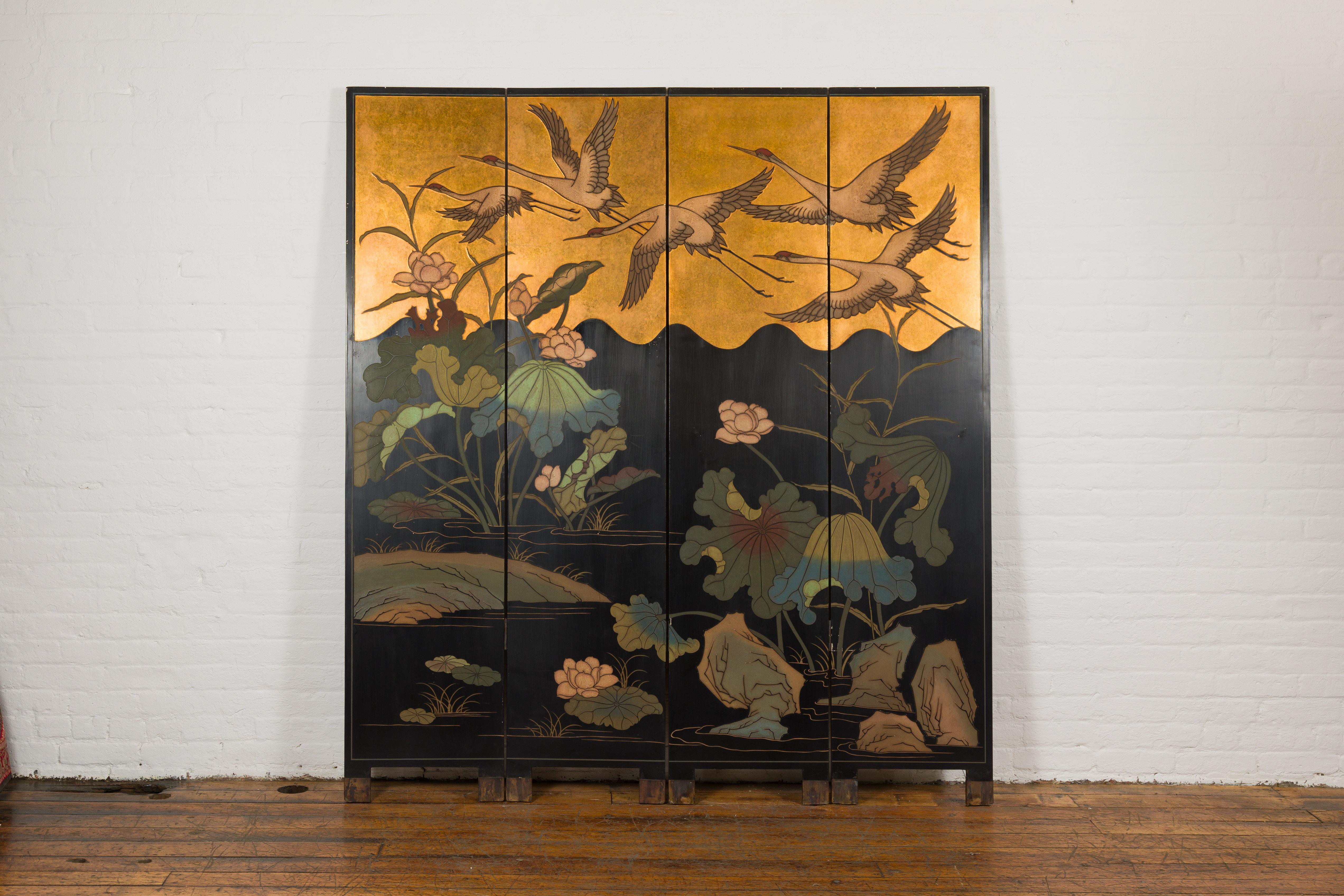 A vintage Chinese Export four-panel Coromandel lacquer folding screen featuring an idyllic pond landscape with five red crowned cranes flying over a pound with lucious vegetation. Embarking upon a poetic journey through timeless Chinese artistry,