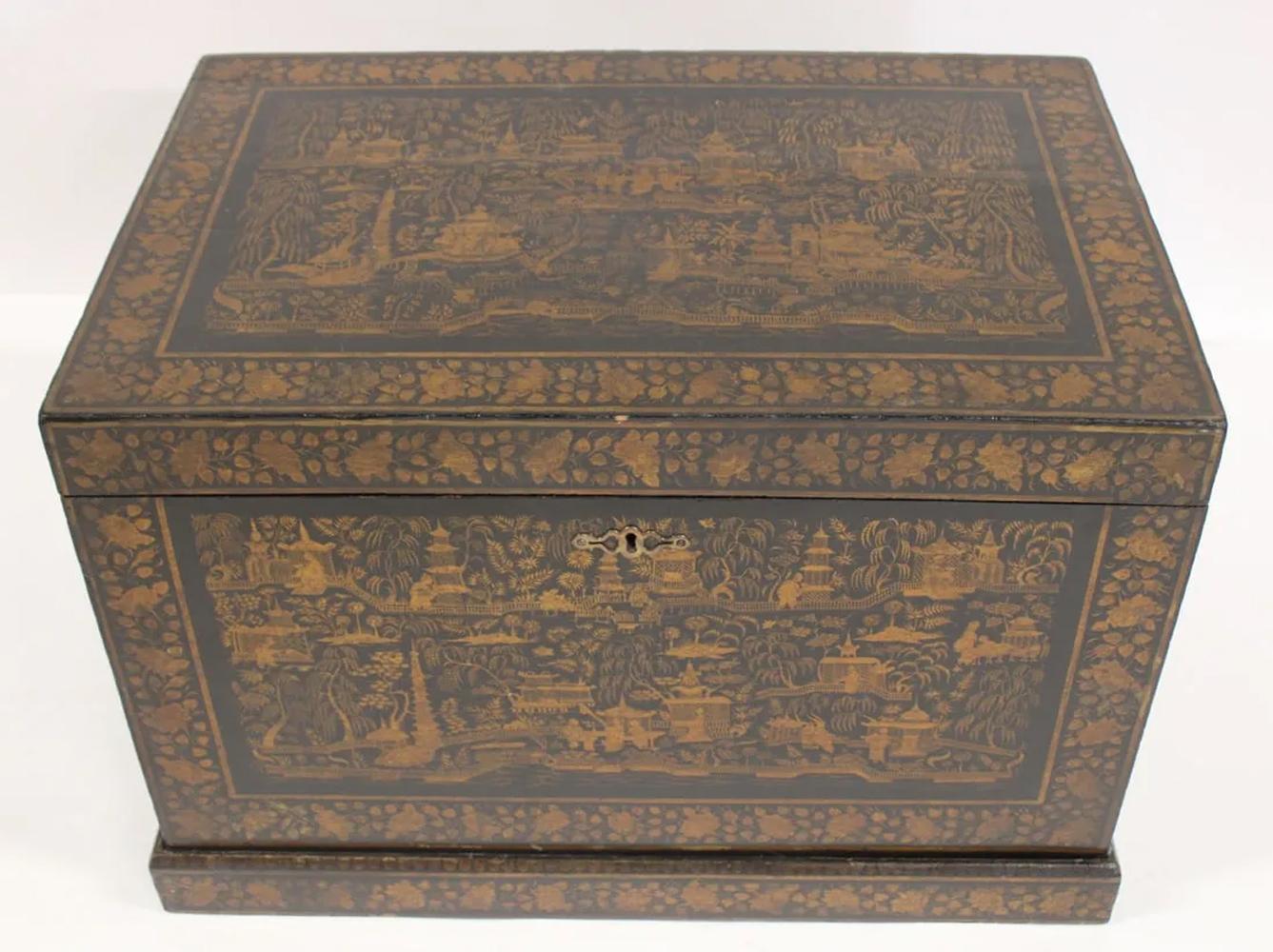China Trade lift-top chest in black lacquer decorated on all four sides and top with landscape and garden scenes with buildings and pagodas with people engaged in various activities all within leaf and vine borders and raised on a separate plinth