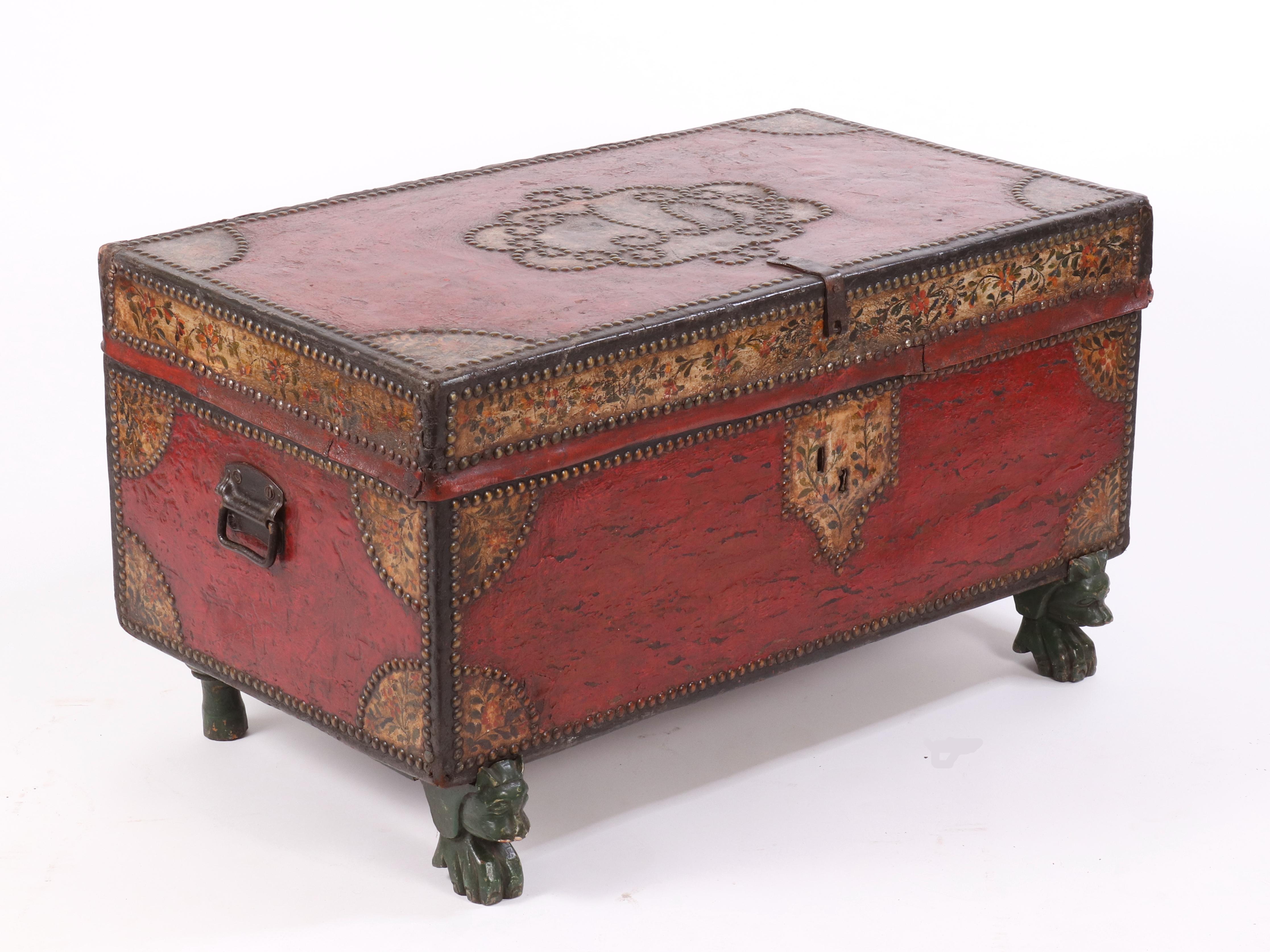 Chinese Export camphor wood and leather trunk with iron carrying handles, painted red with floral borders, corners and escutcheon, decorated with brass tacks; the carved and painted base a later addition.
Measures: 37