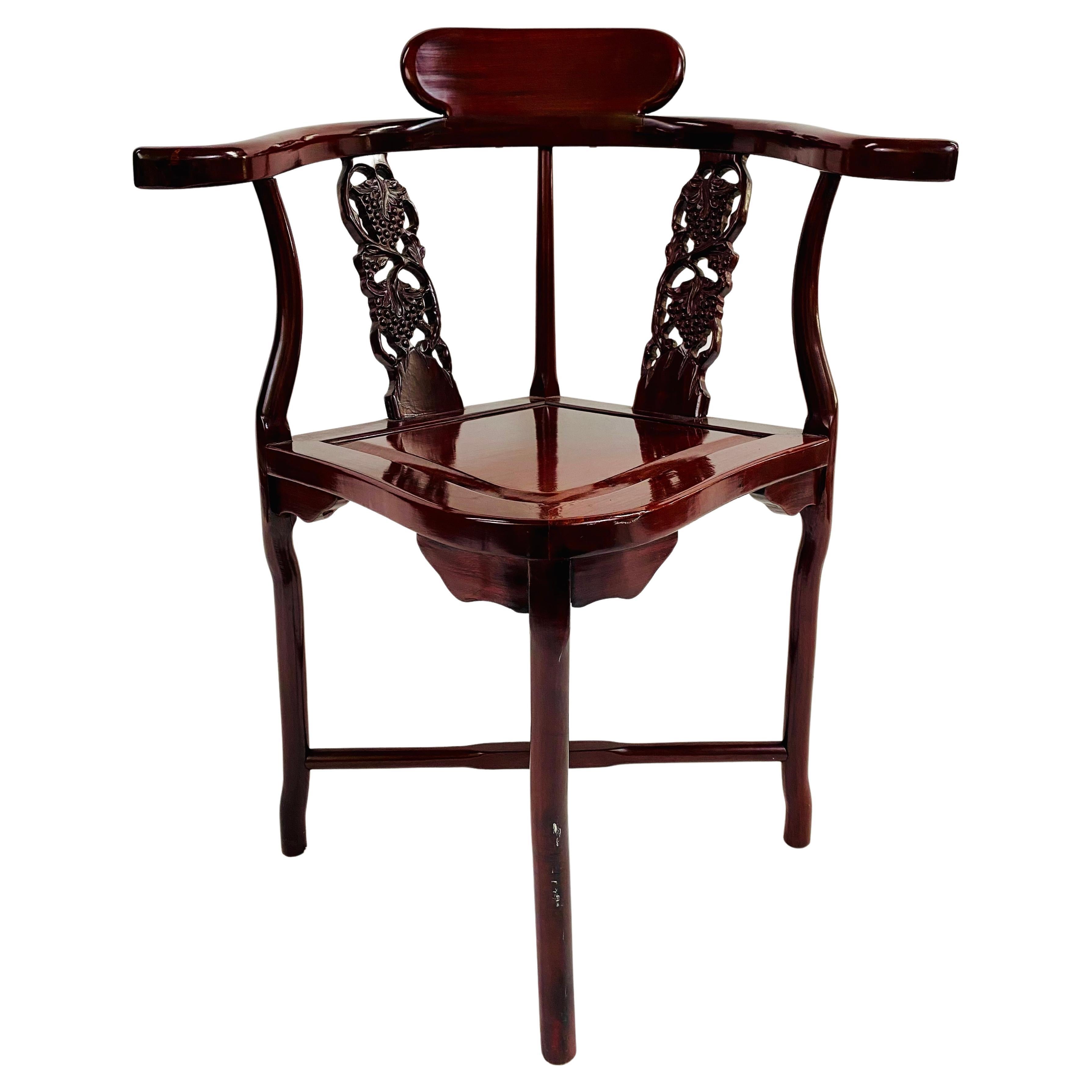 A beautiful Chinese export oriental corner chair. The chair is finely hand-carved of quality rosewood with shiny lacquer finish and is made using tongue and groove technique. The back of the chair shows lovely grapes design and its curvy shape add