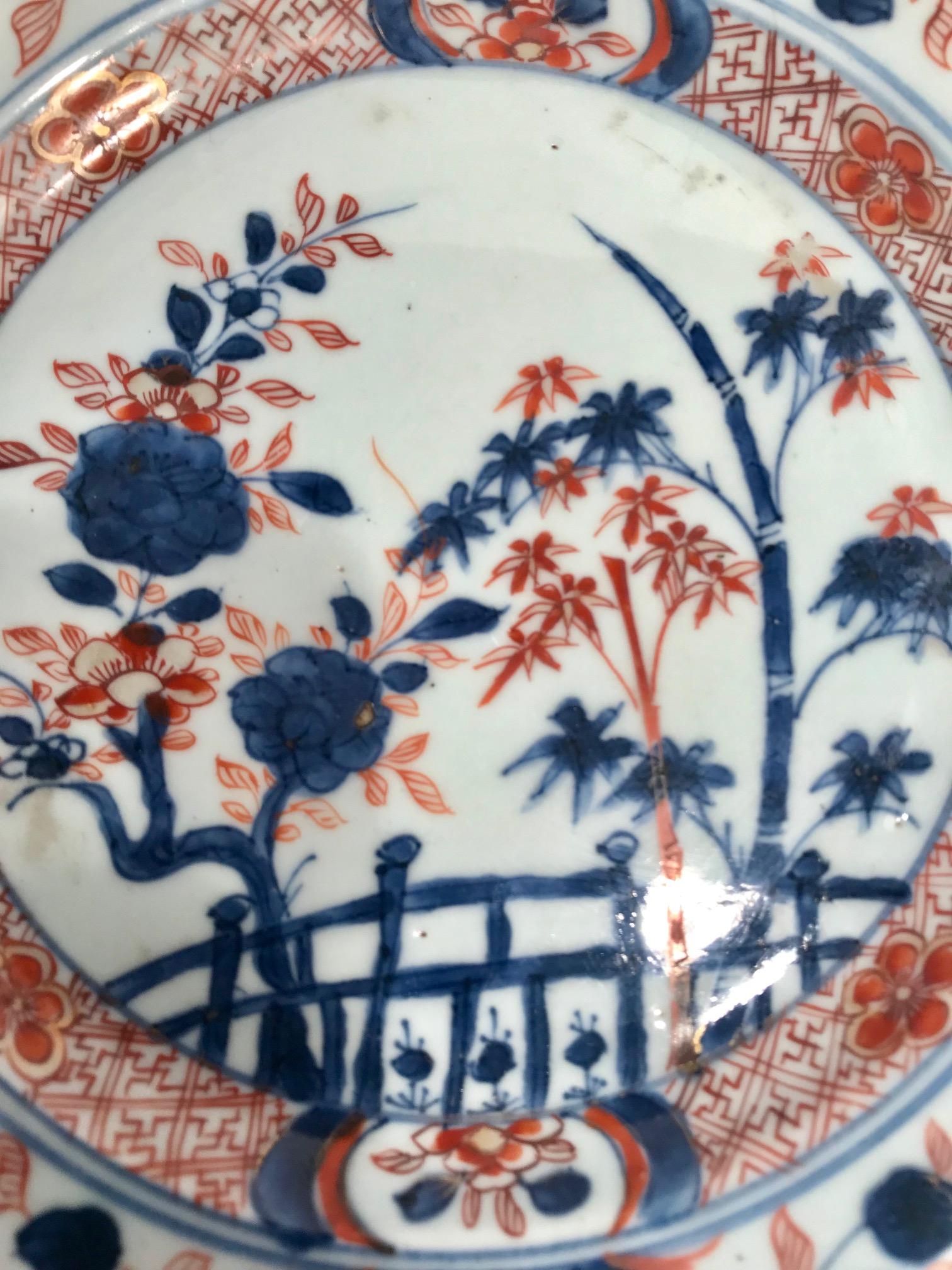 Eighteenth century Chinese Imari export plate. The center scene depicts a garden fence with bamboo and other flowering plants. The border is quite exquisite on this piece. The plate is first hand painted in an underglaze blue and then overpainted in