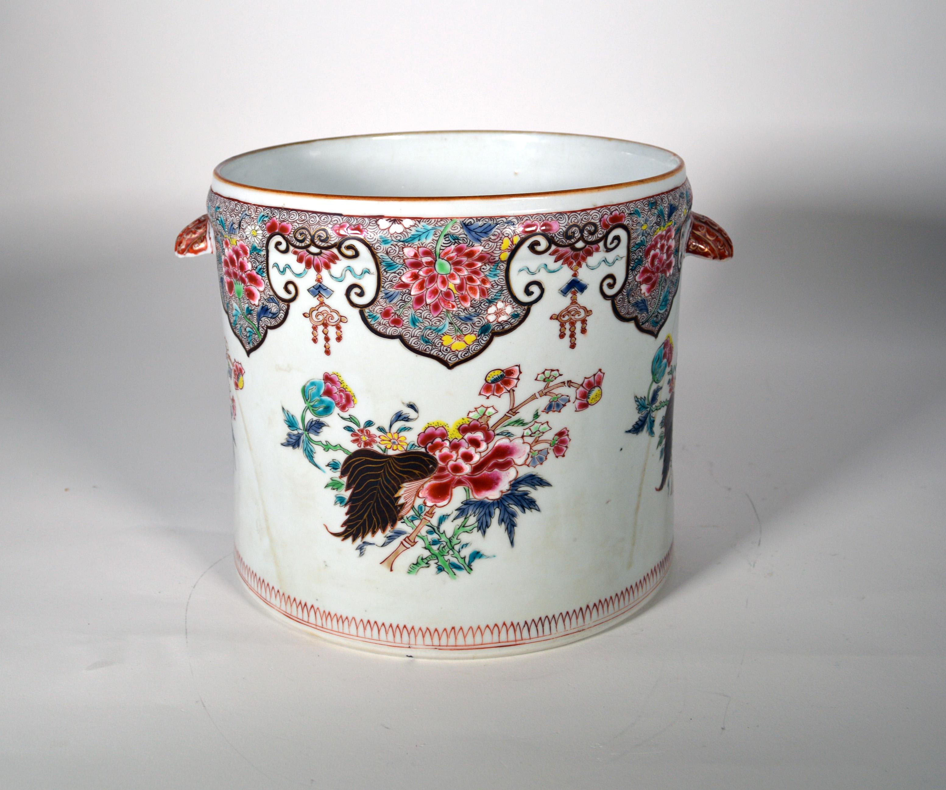 Chinese Export Porcelain Famille Rose Cachepot,
Circa 1750-60
  
The very large Chinese Export porcelain cachepot is of cylindrical form with an inverted shell handle to each side. There is a grouping of bamboo and peony plants to each side, and