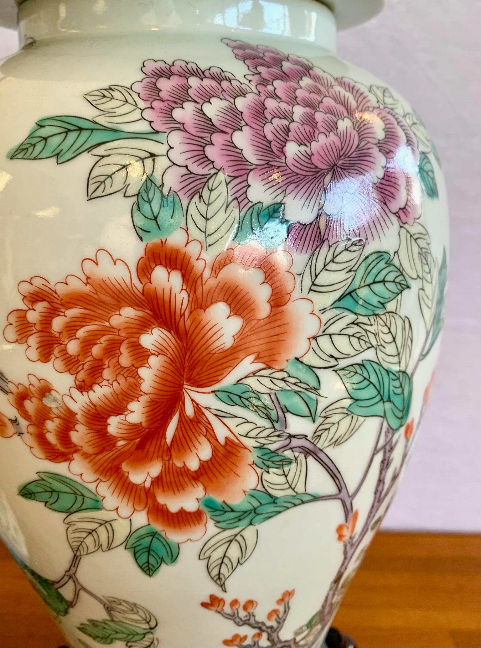 A pair of tall Chinese Export ginger jars handpainted with peonies and butterflies. Displayed on a carved wood base. Height below includes the base.