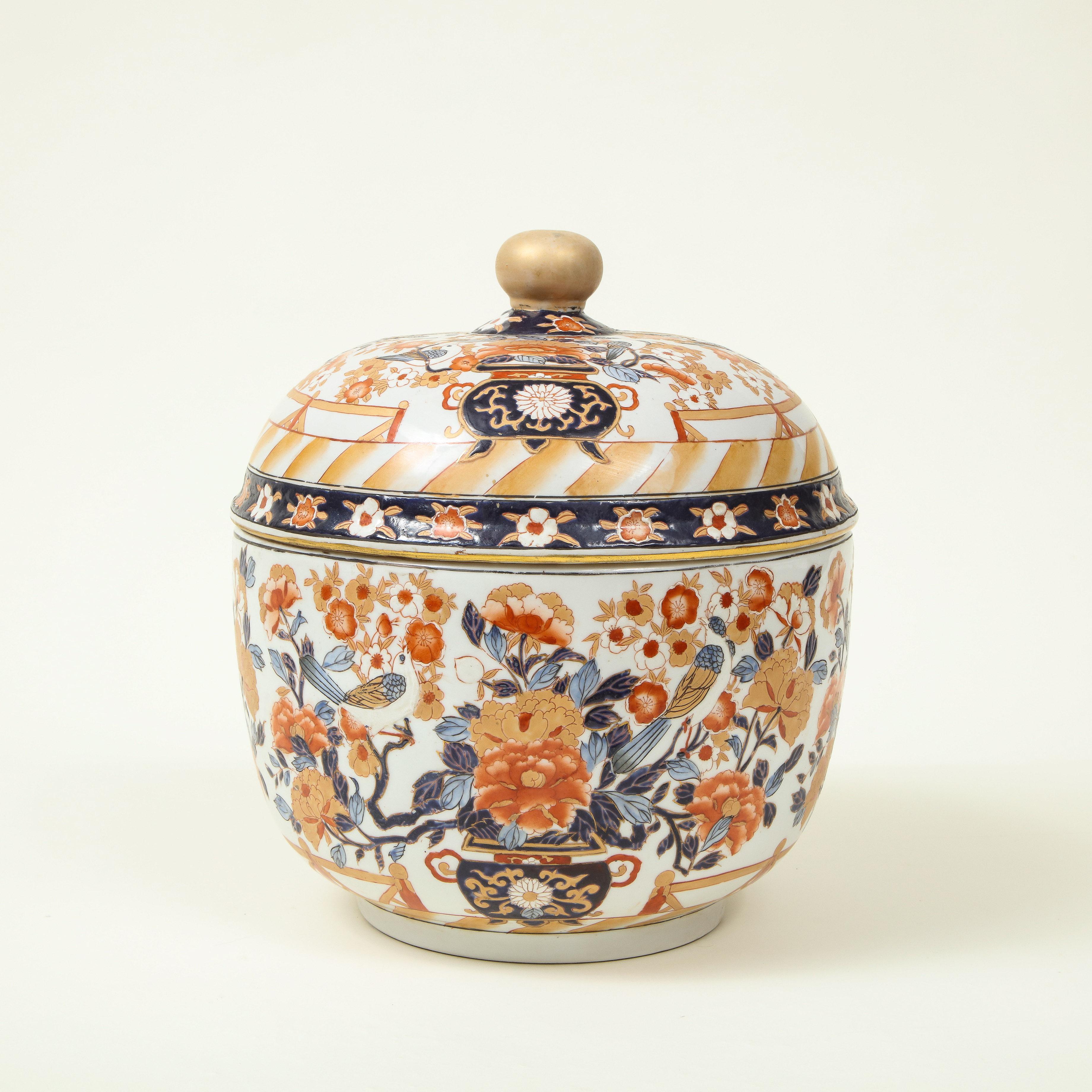 Of globular form with lid surmounted by a gilt ball finial; decorated in iron red and cobalt blue with vases filled with chrysanthemum, birds, and flowering cherry blossoms; With Chinese mark to underside.

Provenance: From the Collection of Mario
