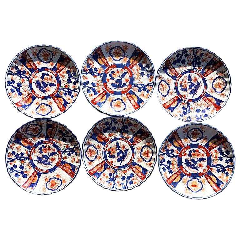 Set of six Chinese export orange and blue imari porcelain plates. (Thought to be from the Kangxi period.) 

This set of plates feature decorative hand-painted designs in blue, orange and red on a white background. The sides are scalloped and painted
