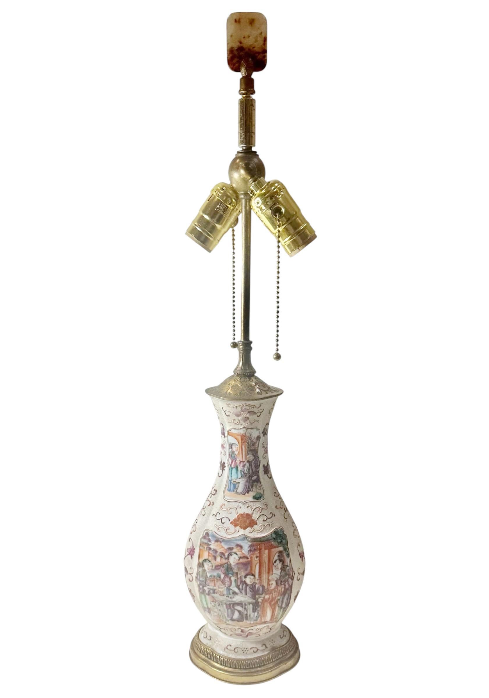 Lampe en porcelaine d'exportation chinoise, début du XIXe siècle, vers 1800, représentant une élégante scène de cour, richement détaillée et montée en bronze doré français. 

Cette pièce unique faisait à l'origine partie d'un ensemble de garnitures