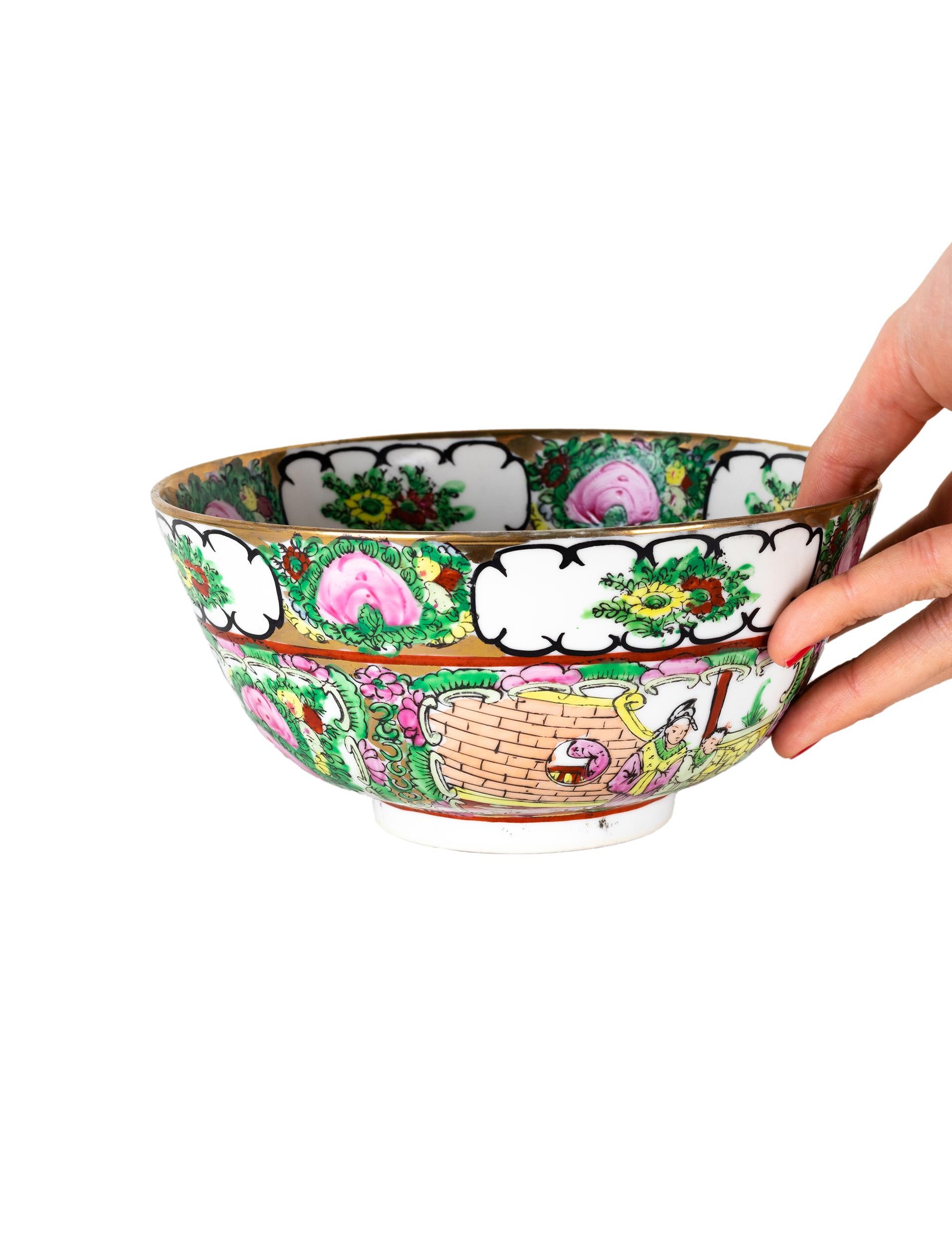 Bol à riz en porcelaine fabriqué à Macao au cours du XXe siècle, présentant la palette emblématique de vert, rose et or avec des scènes florales et figuratives complexes. Chaque panneau est délicatement peint, alternant entre des bouquets luxuriants