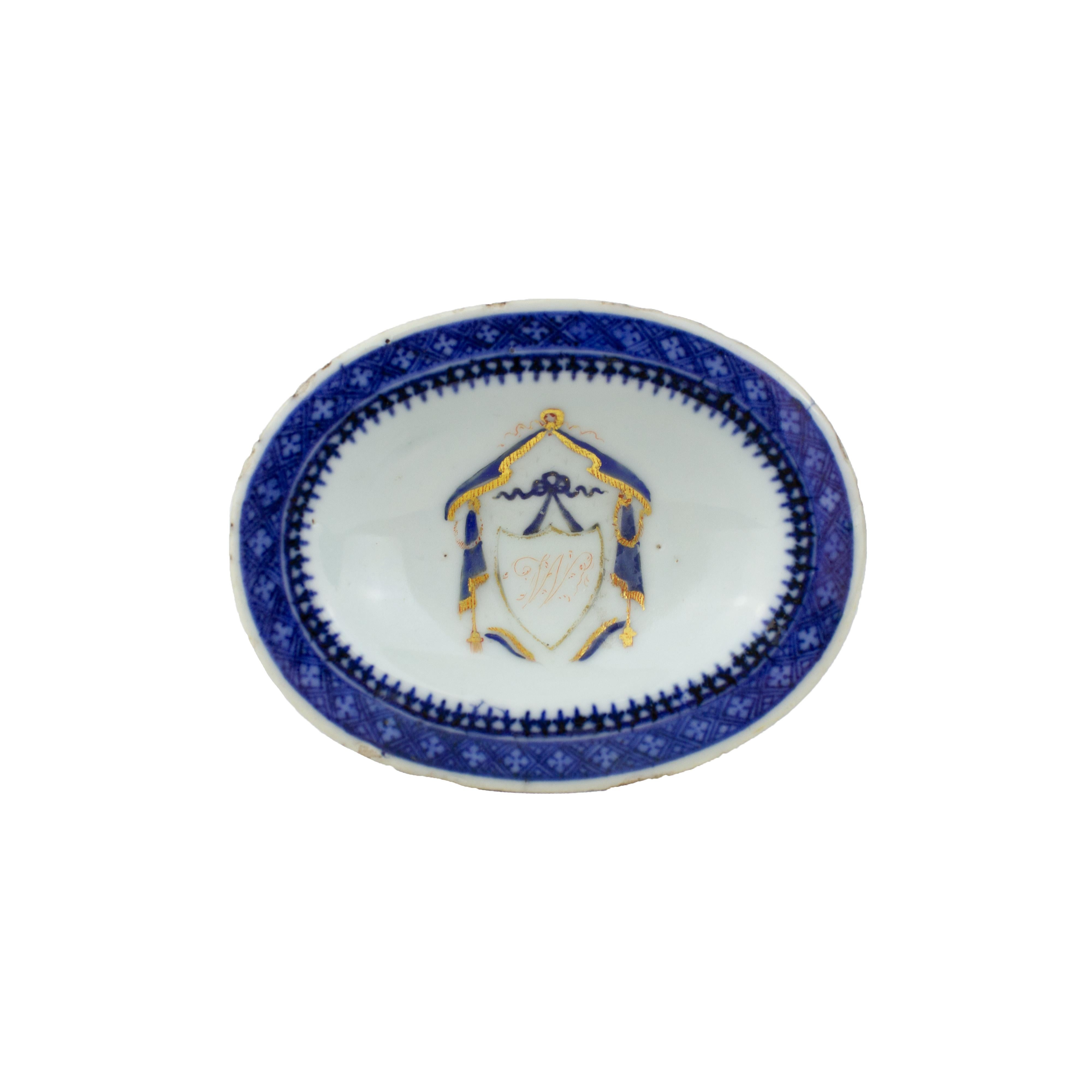 A Chinese porcelain salt-cellar with oval shape, East India Company, Qianlong Period (1736-1795). Underglazed blue decoration representing a geometric pattern and arrow points in both rims and a blue and gilt monogram on the top. 
 