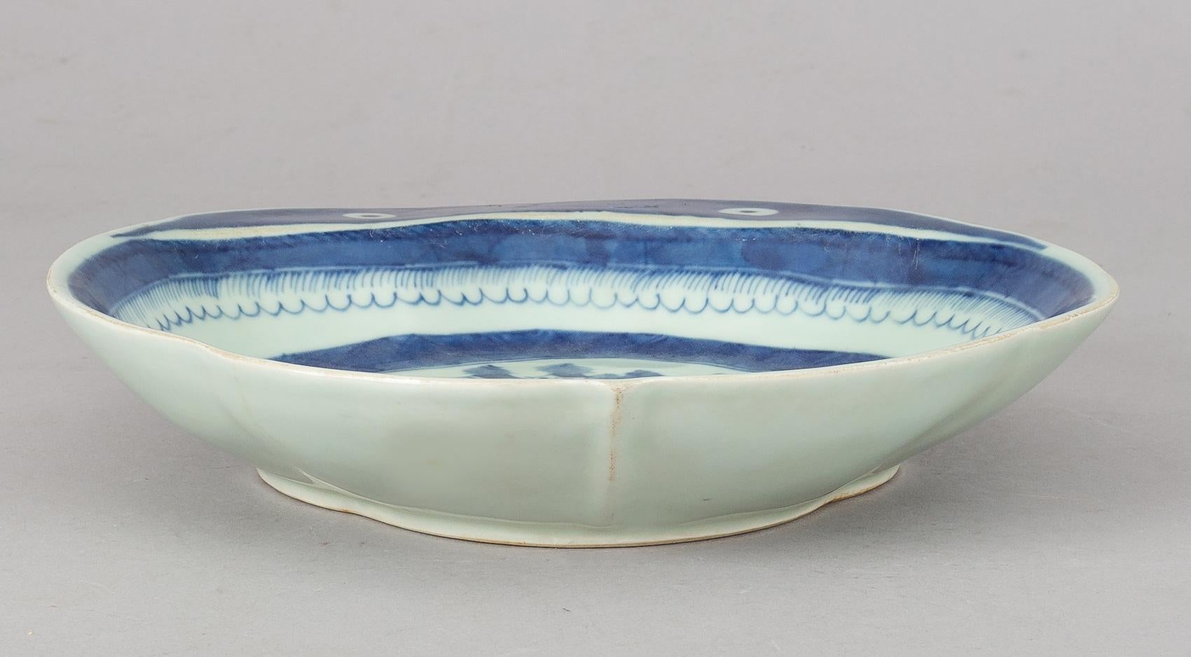 Chinese Export Canton blue and white porcelain lobed shrimp dish, the flange decorated with two eyes, the centre decorated with pagodas, a bridge, boats, trees and rockery.