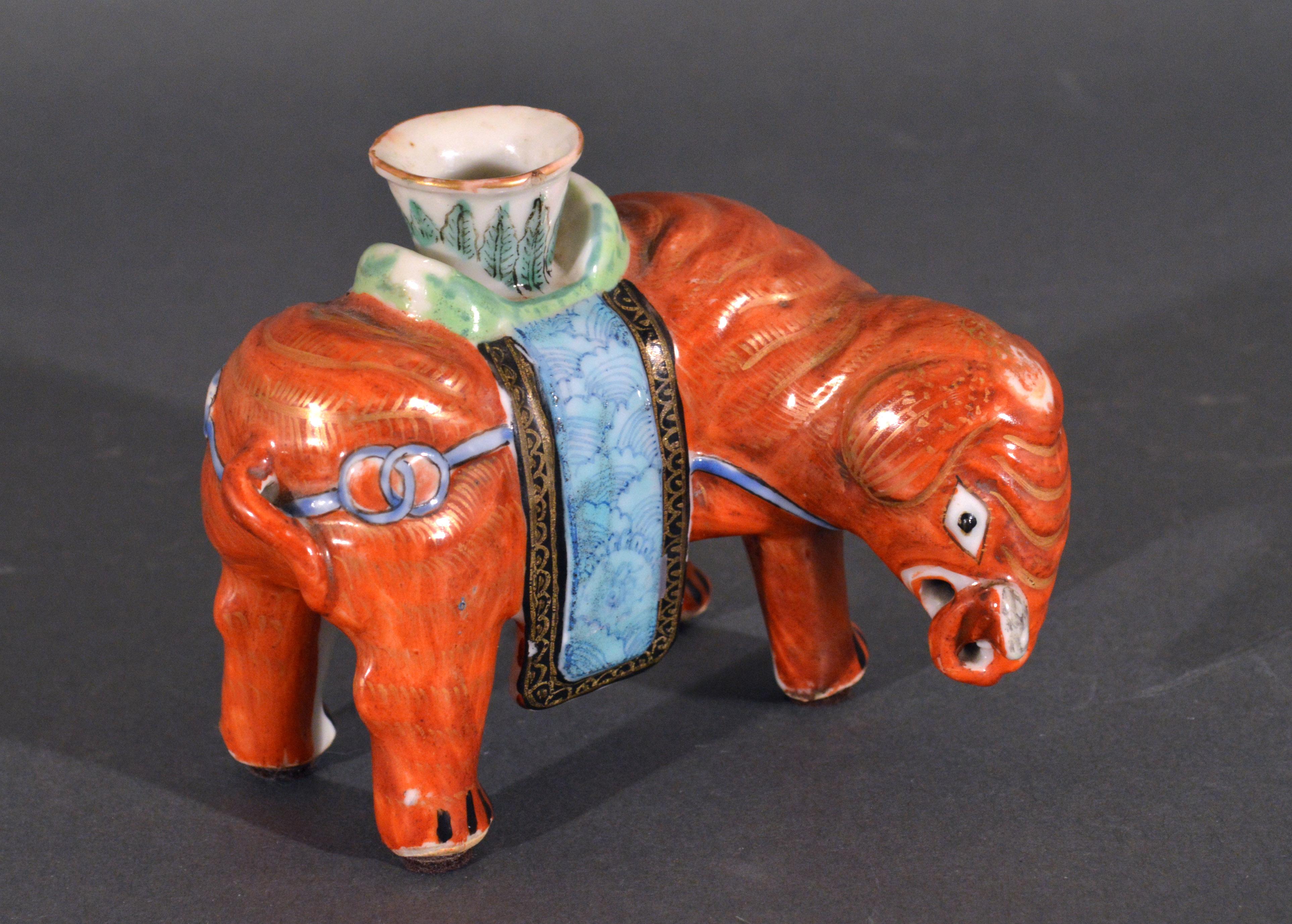 Chinese Export Porcelain small canton famille rose elephant modeled as a candlestick,
circa 1860 

The standing Chinese Export porcelain elephant with its trunk up is painted in an iron-red with gilt decoration. On its back is a vase-shaped