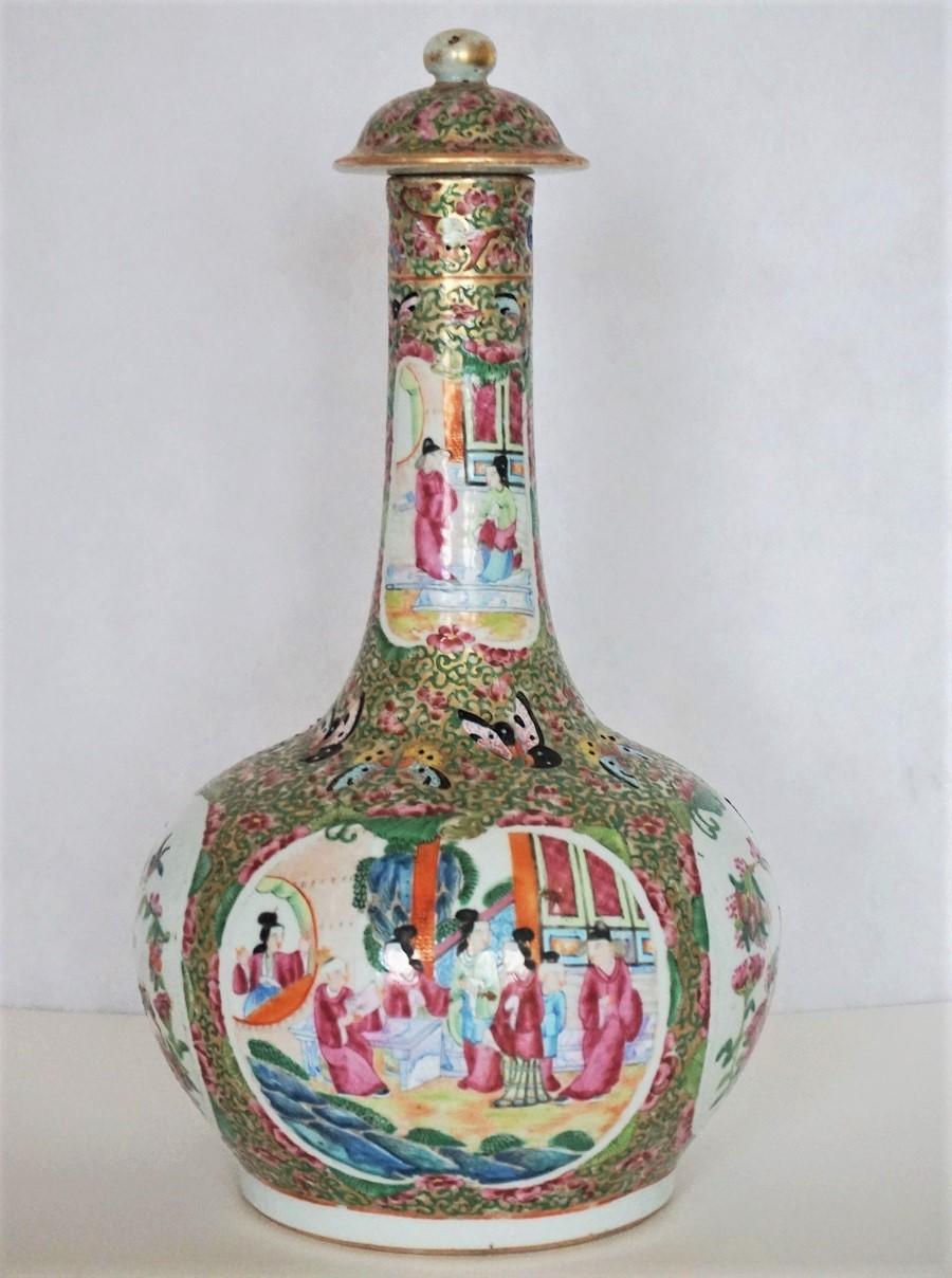 Early 19th century rose mandarin lidded bottle vase, typically decorated in the 'Rose Medallion' pattern. Two panels depicting Chinese garden and interior scenes and two panels with birds, butterflies and flowers.
Restoration to the neck of the